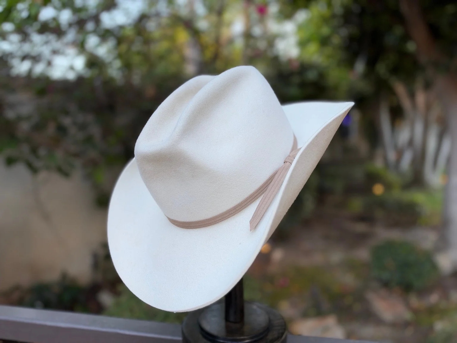 Angled view of Der Freiherr ivory Western hat showing the sand-colored ribbon band and trailing ends.