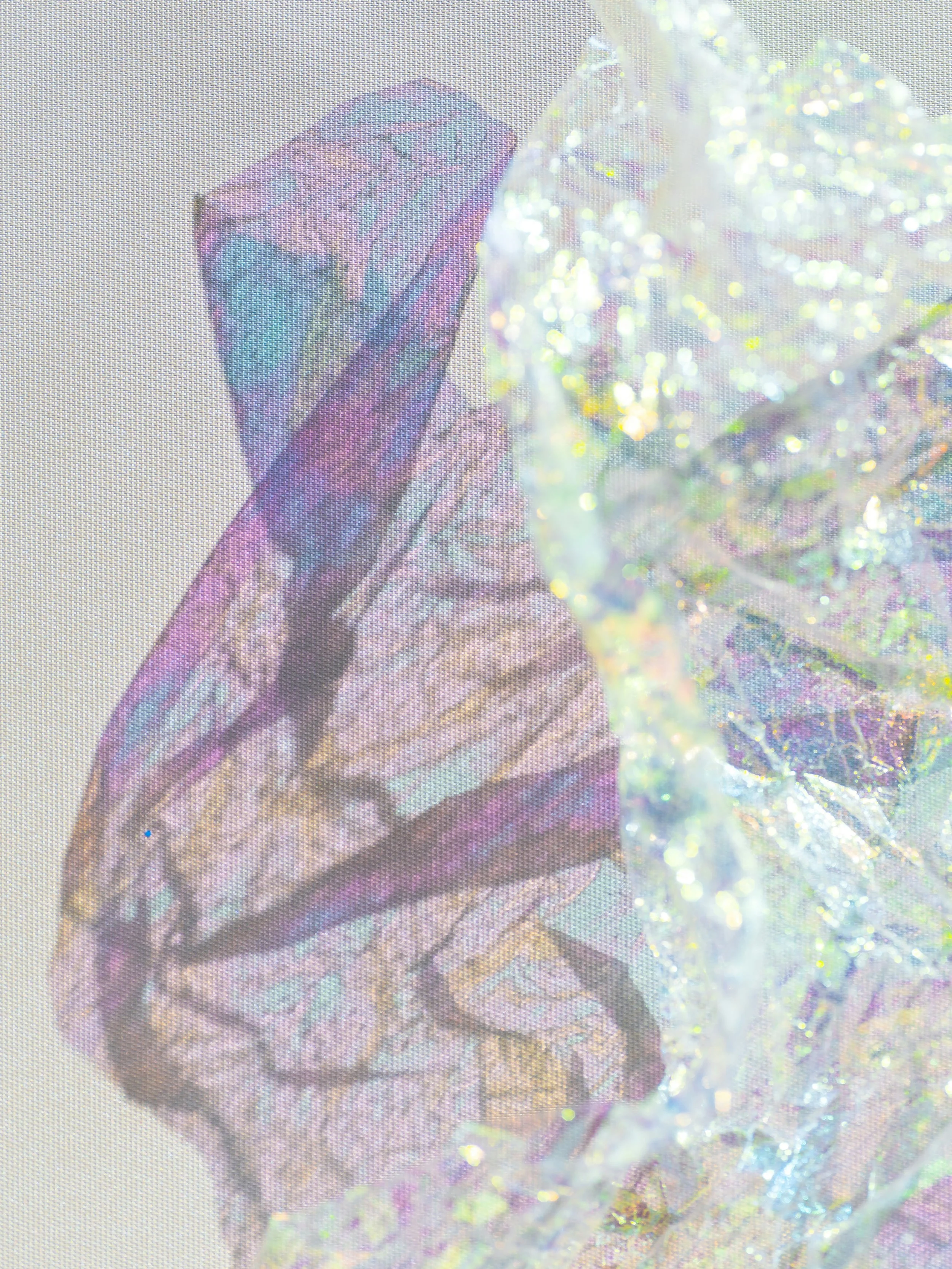 Close-up of a sparkly, iridescent craft ribbon or decoration with holographic, shiny, multicolored surface and a hand holding it.