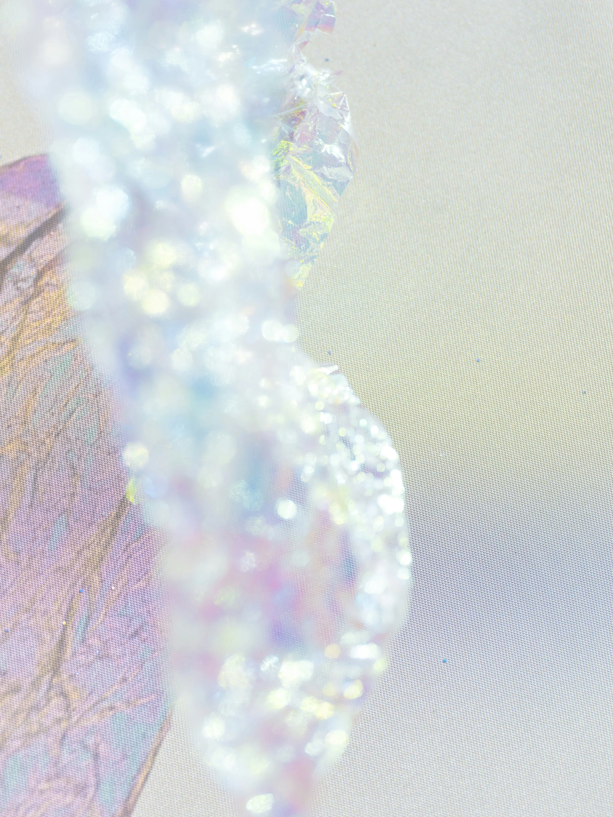 Close-up of iridescent glitter and holographic material on a light background.