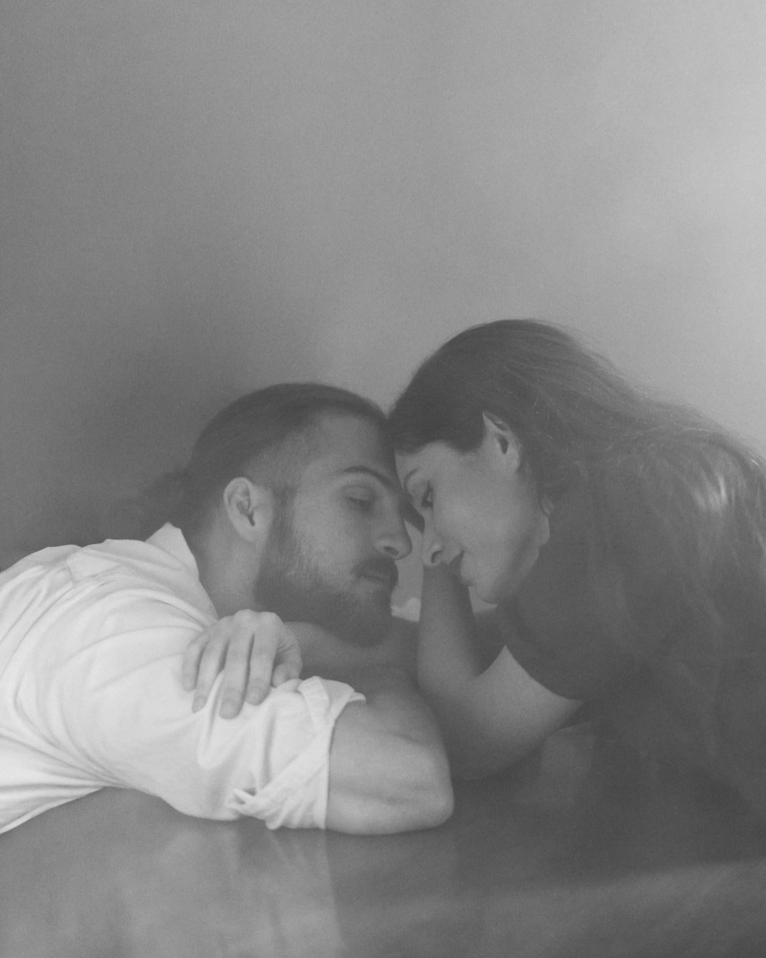 Una pareja compartiendo un momento íntimo y romántico, con gestos dulces en el rostro.