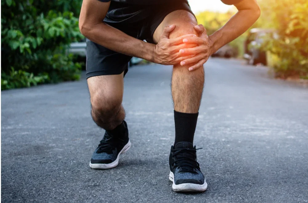 Man squatting, holding knee that looks inflamed
