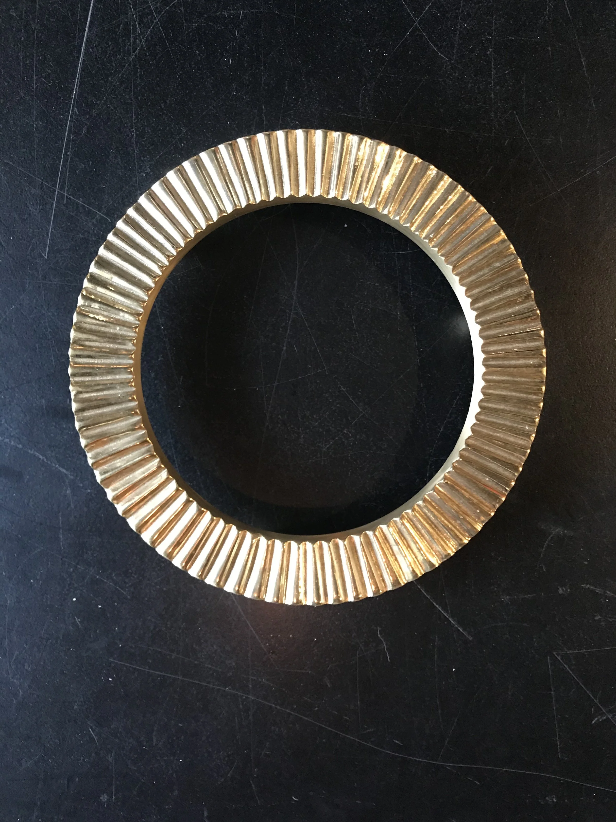 A woman with shoulder-length black hair smiling in a greenhouse or garden with greenery around her.