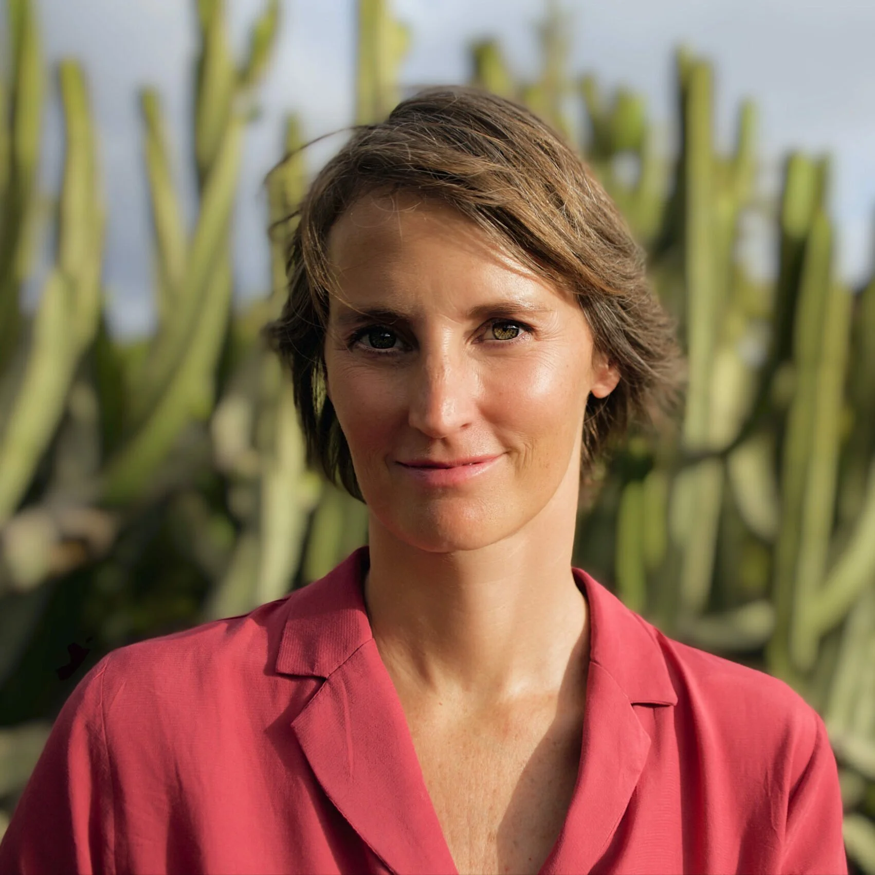 Woman in red shirt in front of cacti, outdoors
