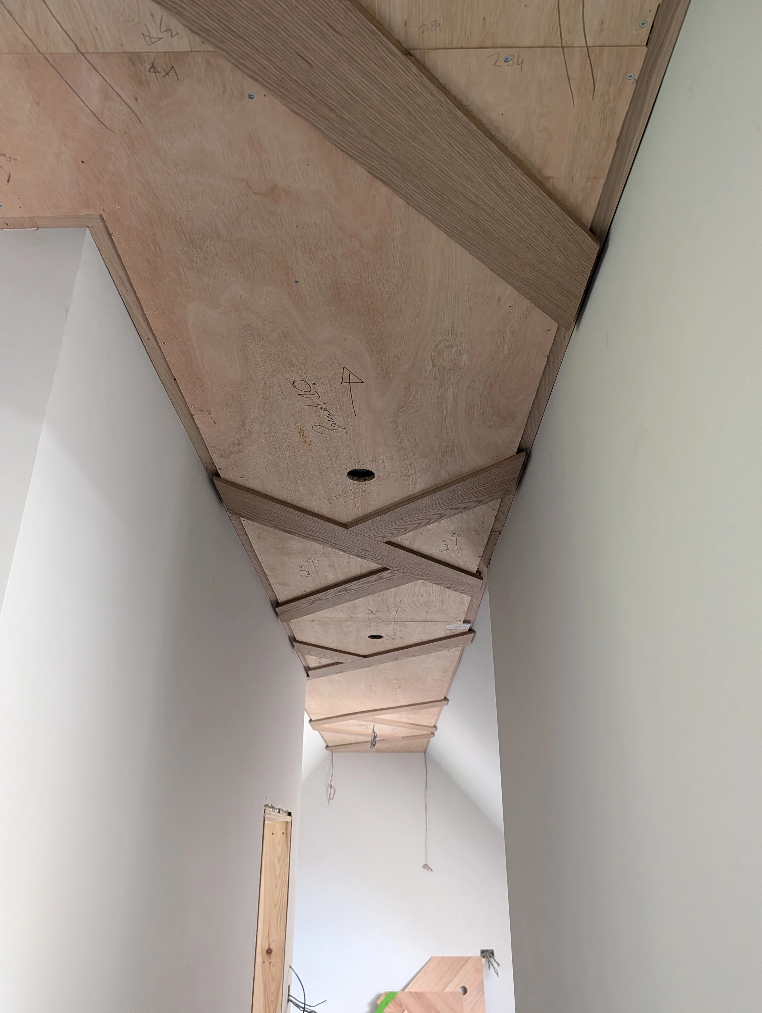 Bespoke geometric timber ceiling with integrated warm lighting by Clark & Prince