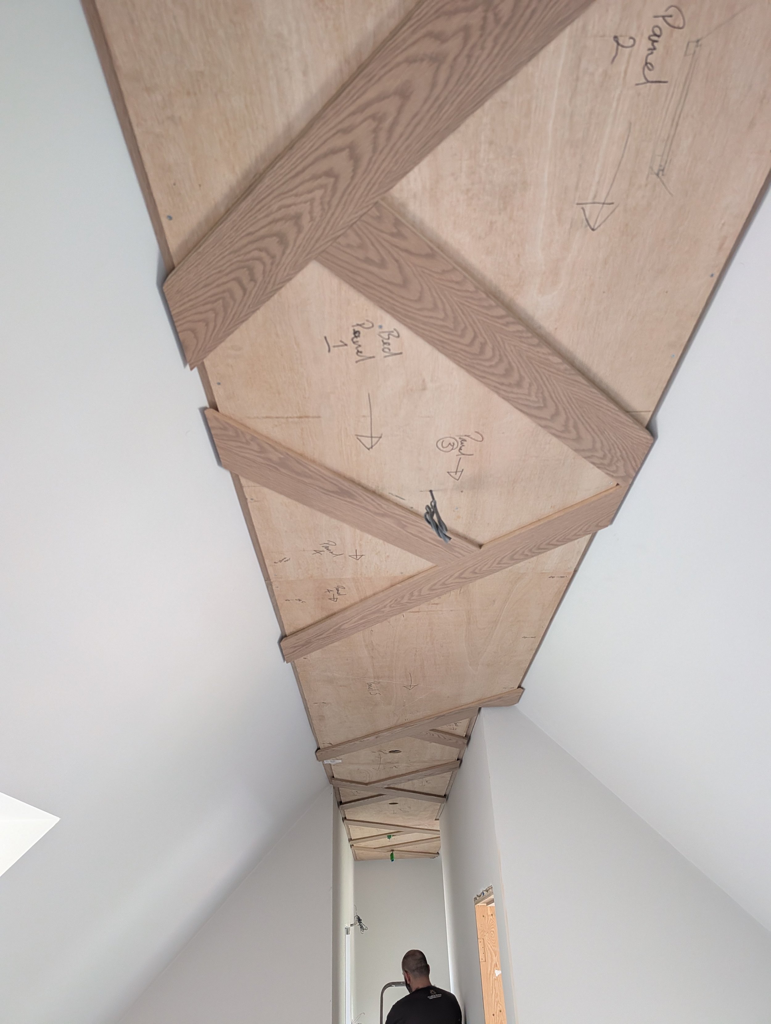 Bespoke geometric timber ceiling with integrated warm lighting by Clark & Prince
