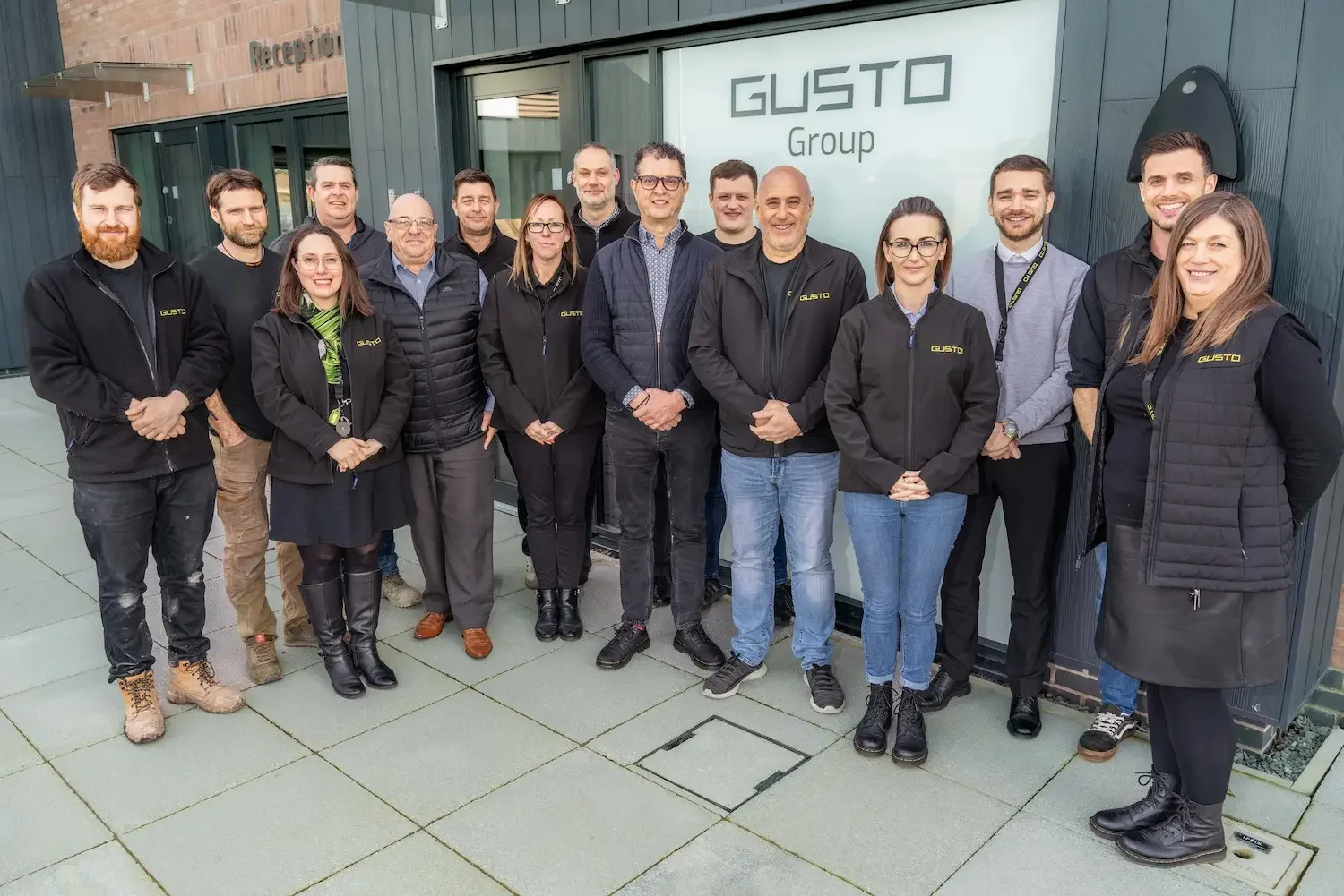 A group of people in black clothing stood outside the reception of their offices at Gusto House