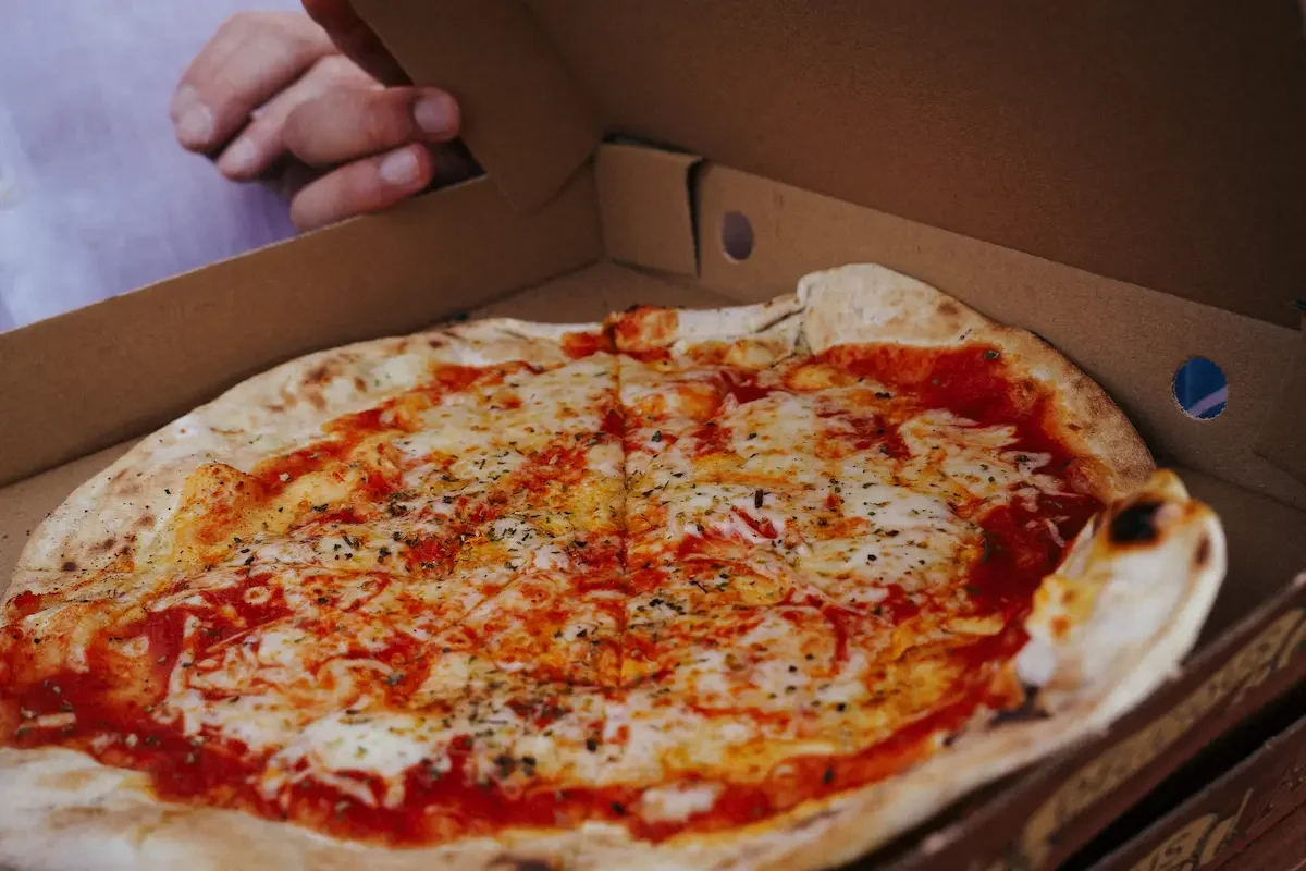 A margarita pizza in a cardboard pizza bos