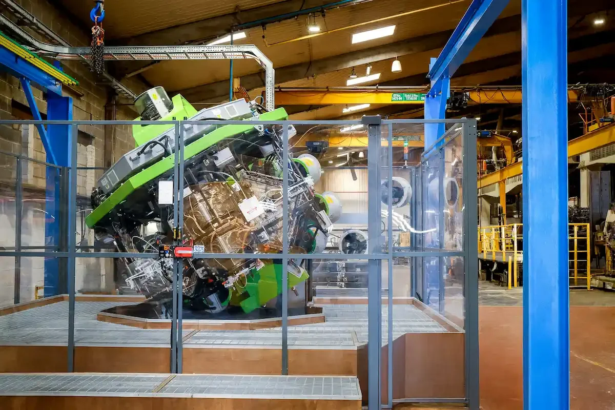 A massive green Persico SMART Machine in the middle of a factor floor, situated behind some clear doors.