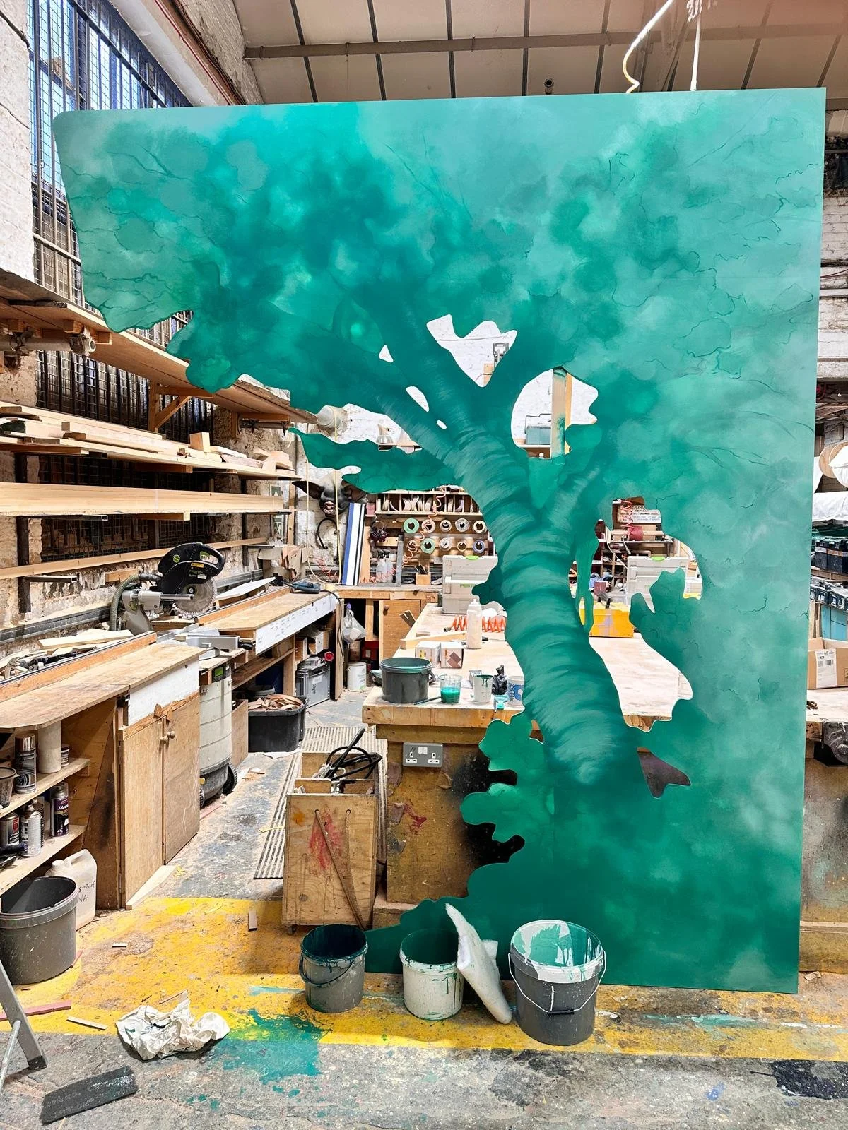Hand-painted scenic backdrop in production at the Andy Knight workshop, featuring a bespoke tree motif created to establish depth and atmosphere within the photographic environment.