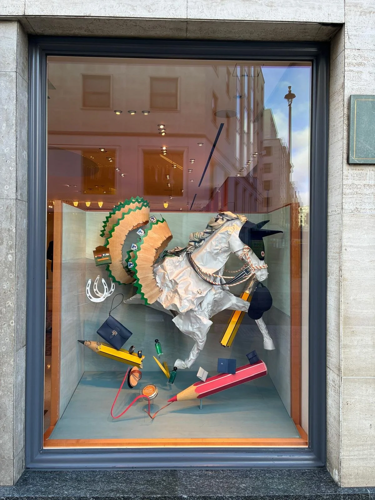 Christmas window display for Hermès in London, designed by Shona Heath, featuring a sculptural horse emerging from a painted backdrop into a satin fabric snow landscape.