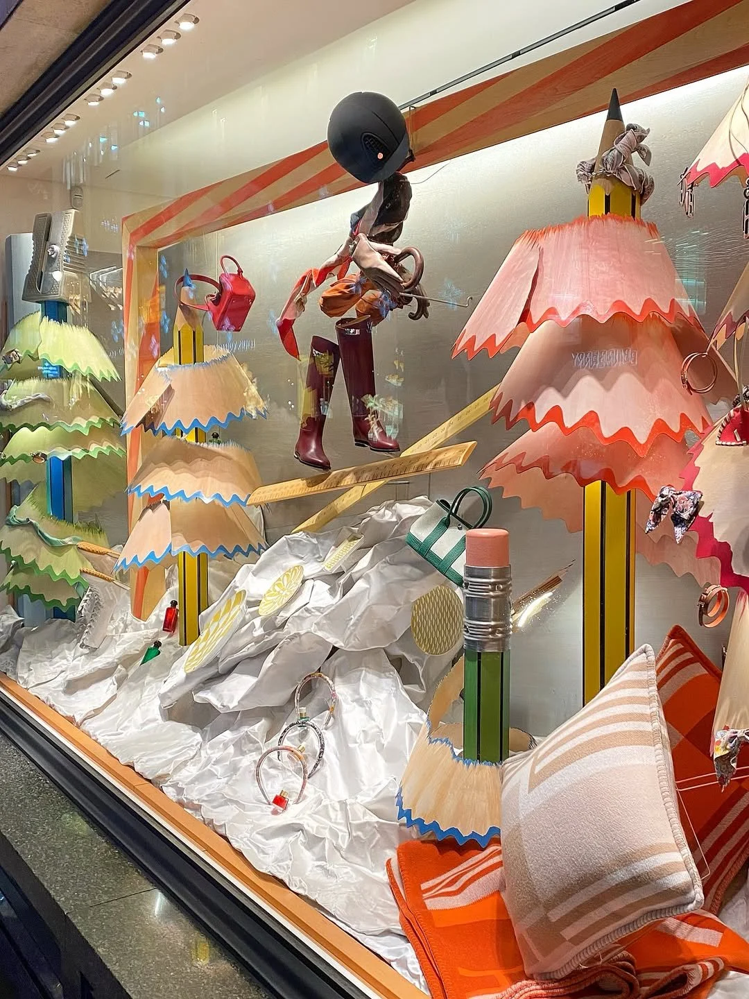 A close up image of the bespoke Christmas window installation for Hermès, designed by Shona Heath and built by Andy Knight, including oversized wooden pencil trees and wood veneer pencil shavings with washed paint effect.  The window landscape is scu