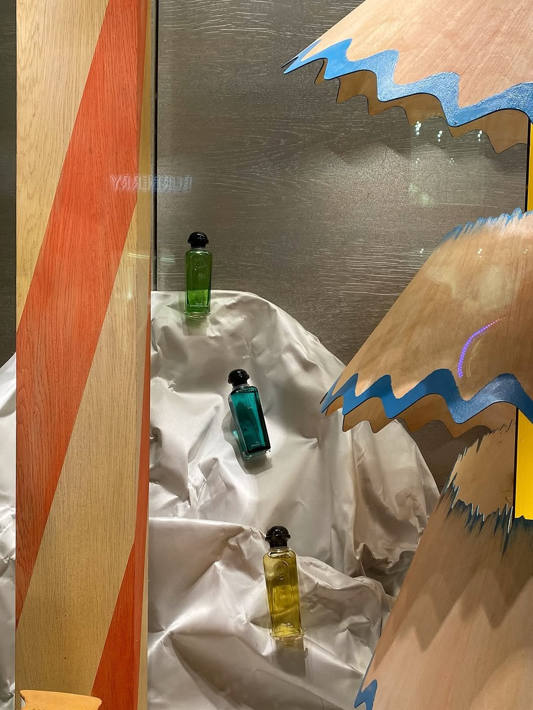 close up image of the Hermes perfume products positioned and mounted on top of the satin sculpted landscape in the Christmas window display for Hermès in London, designed by Shona Heath.