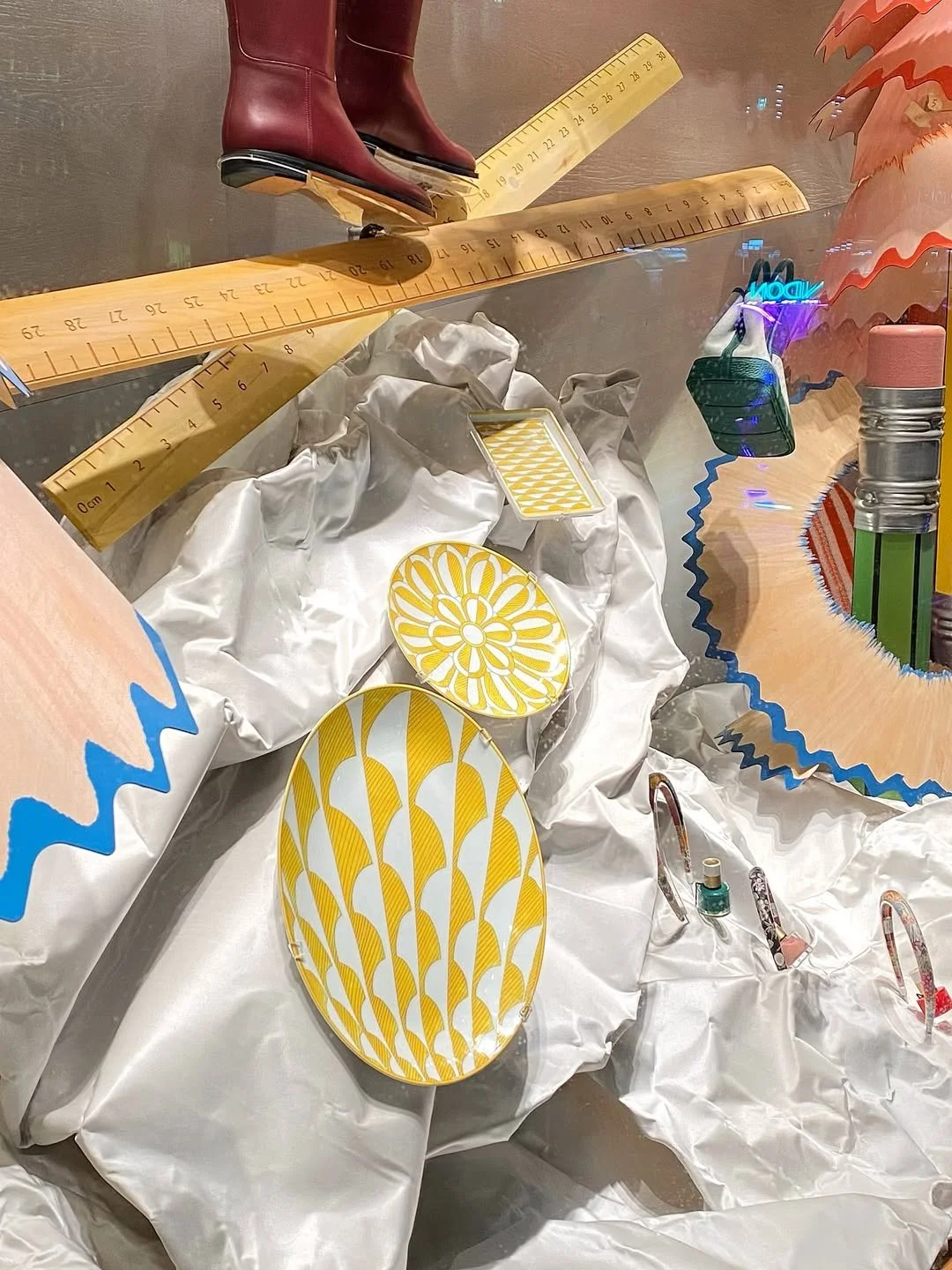 Close ups of the Hermes plate  products mounted onto the satin fabric landscape in the Christmas window display for Hermès in London, designed by Shona Heath,