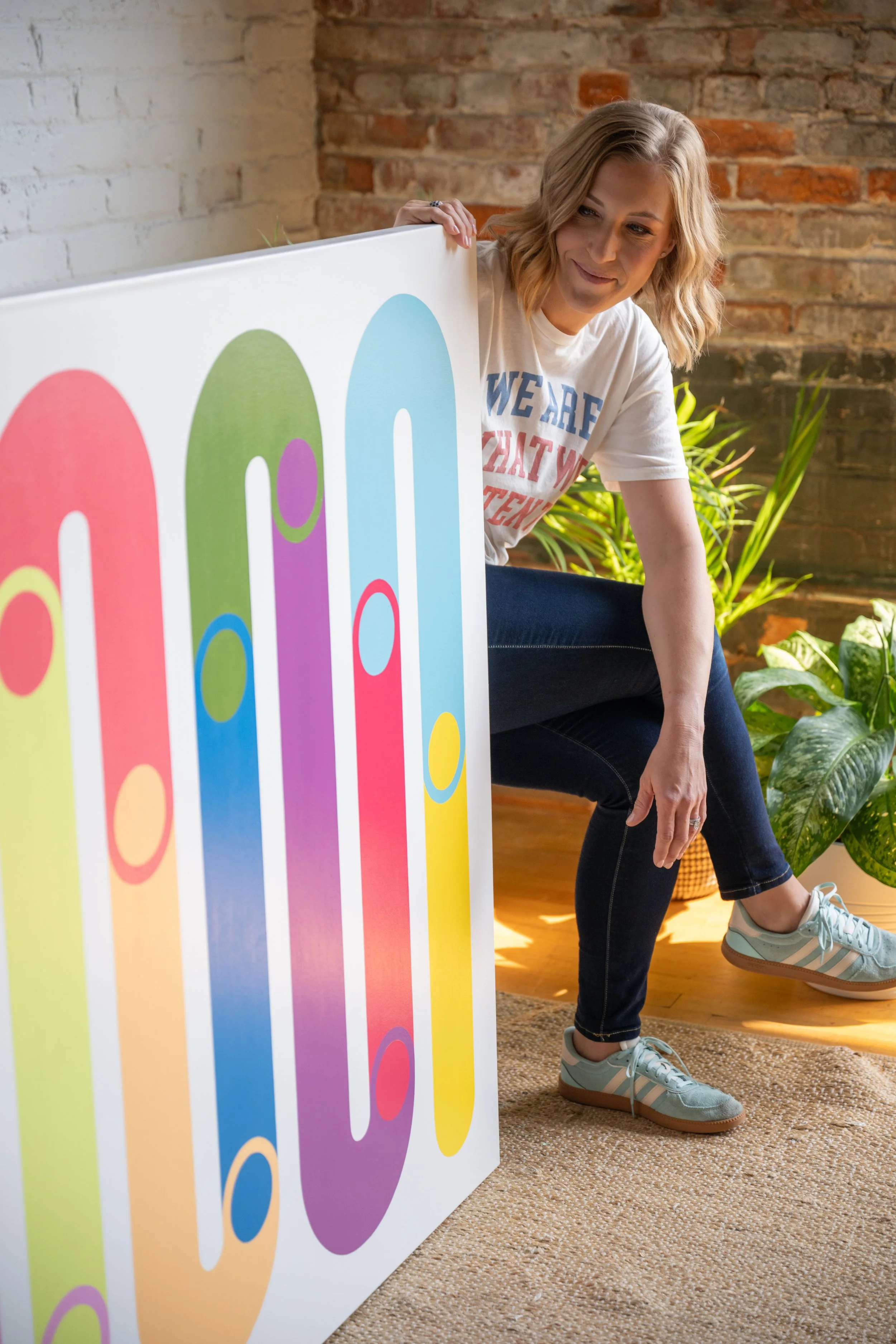 Contemporary abstract artist Merrill Moore with large-scale geometric artwork from the Momentum collection. The colorful elongated forms and layered composition explore movement, transition, and the shifting roles we move through in everyday life.