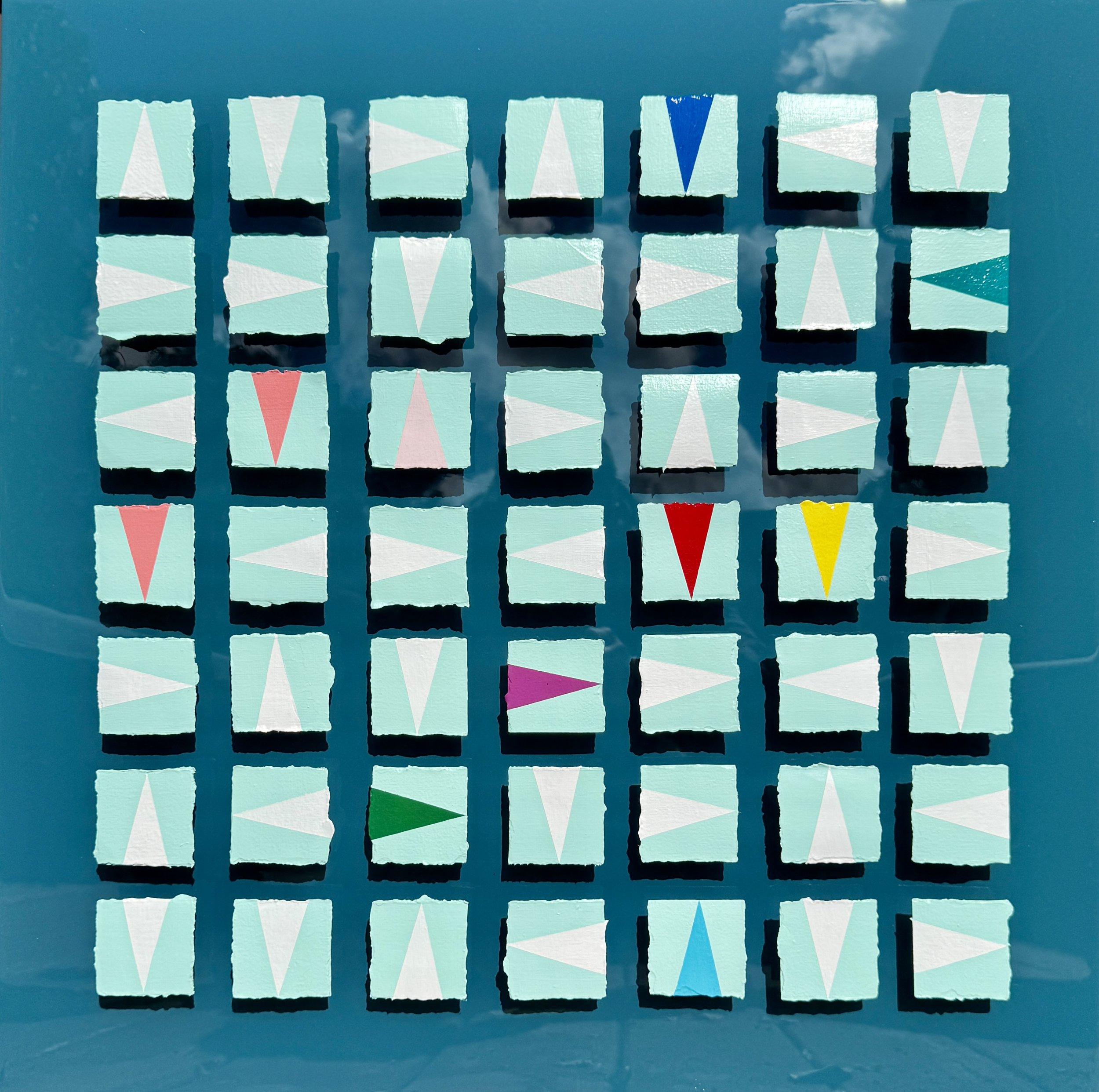 Caught in the Crosswinds explores movement, direction, and shifting momentum through layered geometric forms and reflective resin surfaces. Inspired by nautical signals and changing currents, the high-gloss background captures reflections of the sky 