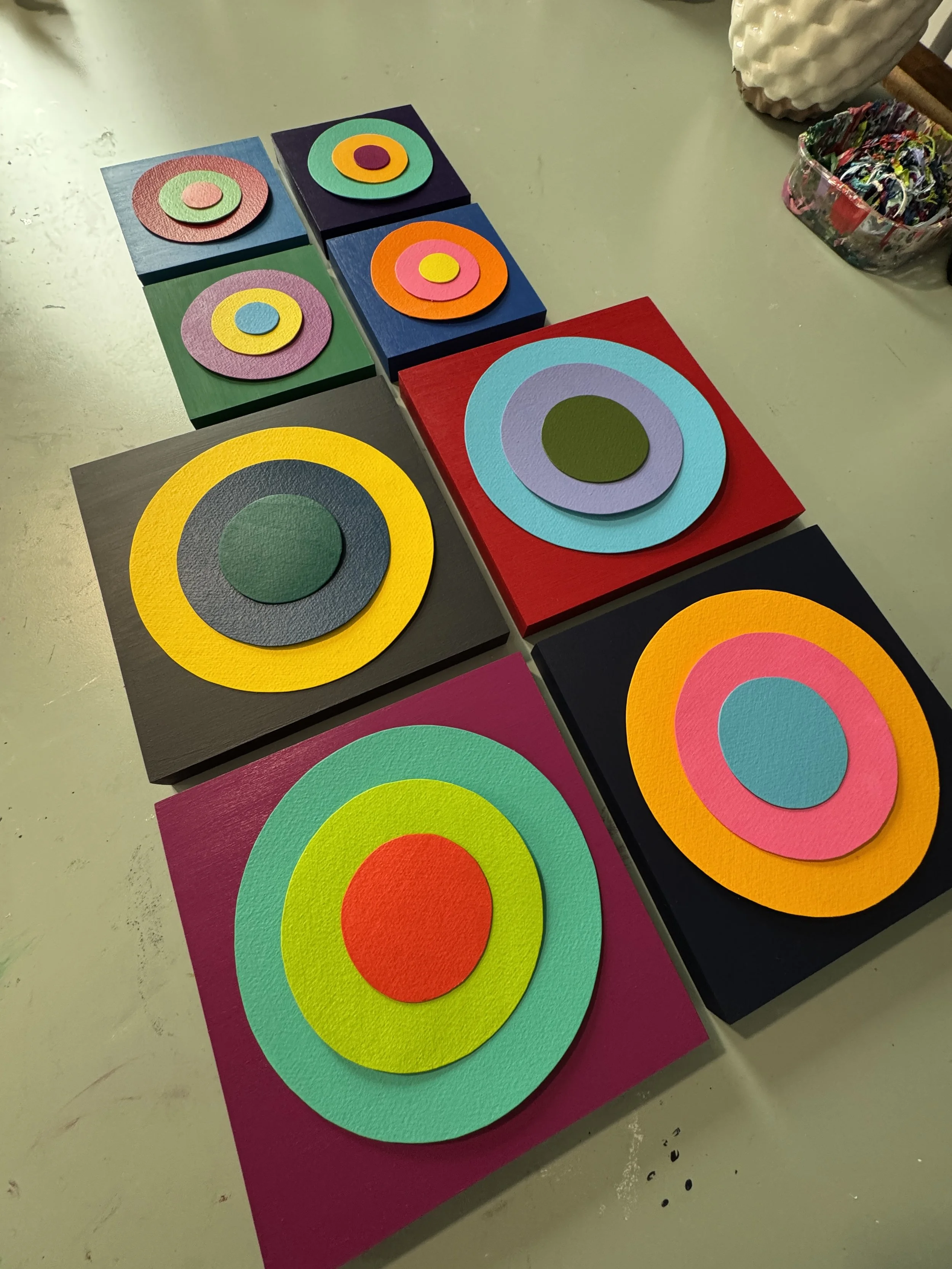 These small-scale Taking Aim pieces combine bold geometric compositions with layered dimensional elements and high-gloss resin surfaces. Exploring focus, direction, and personal momentum, each work uses vibrant color relationships and reflective fini
