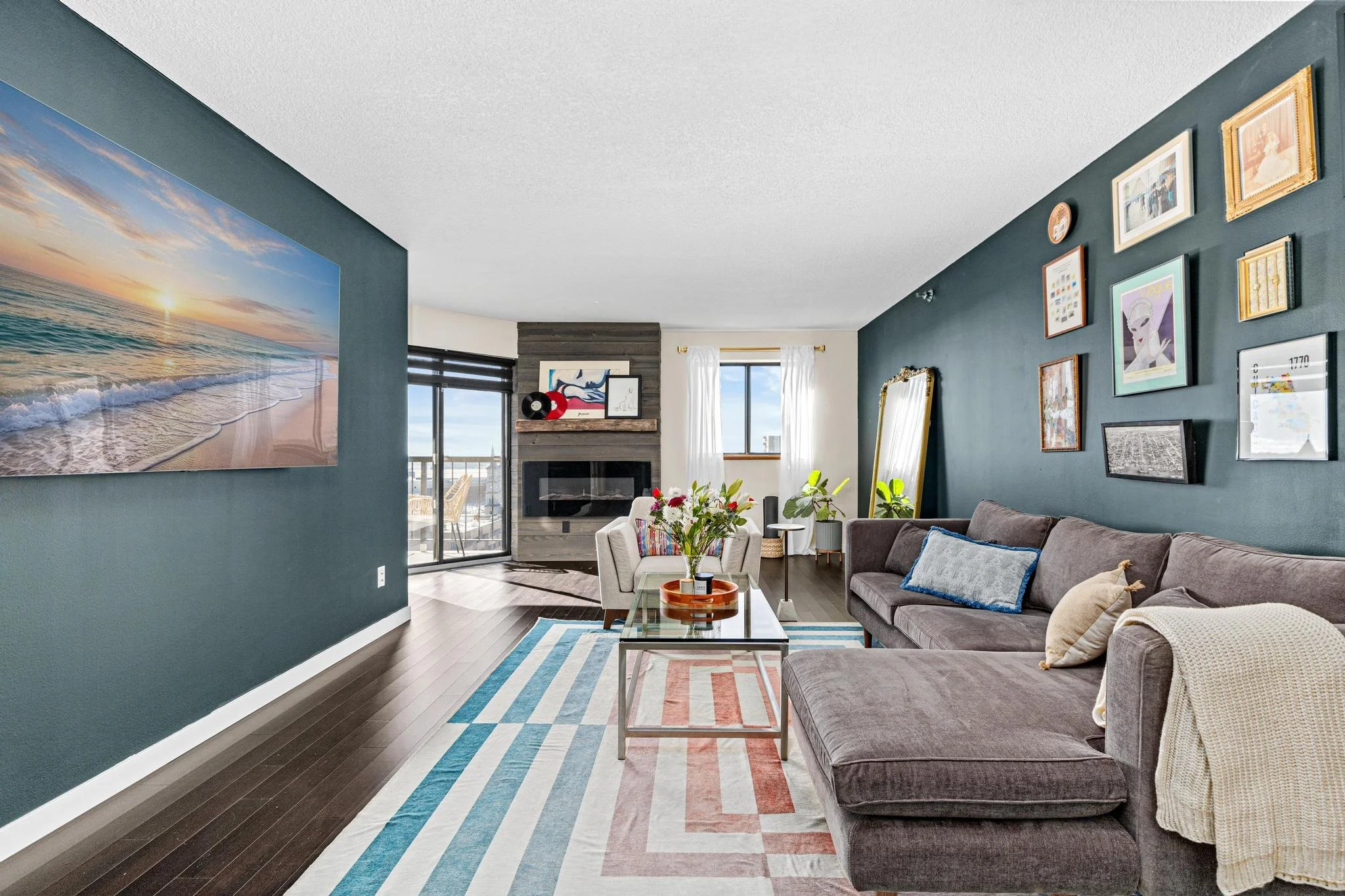 Living room with dark gray sofa, wall gallery, and an abstract painting of a beach at sunset.