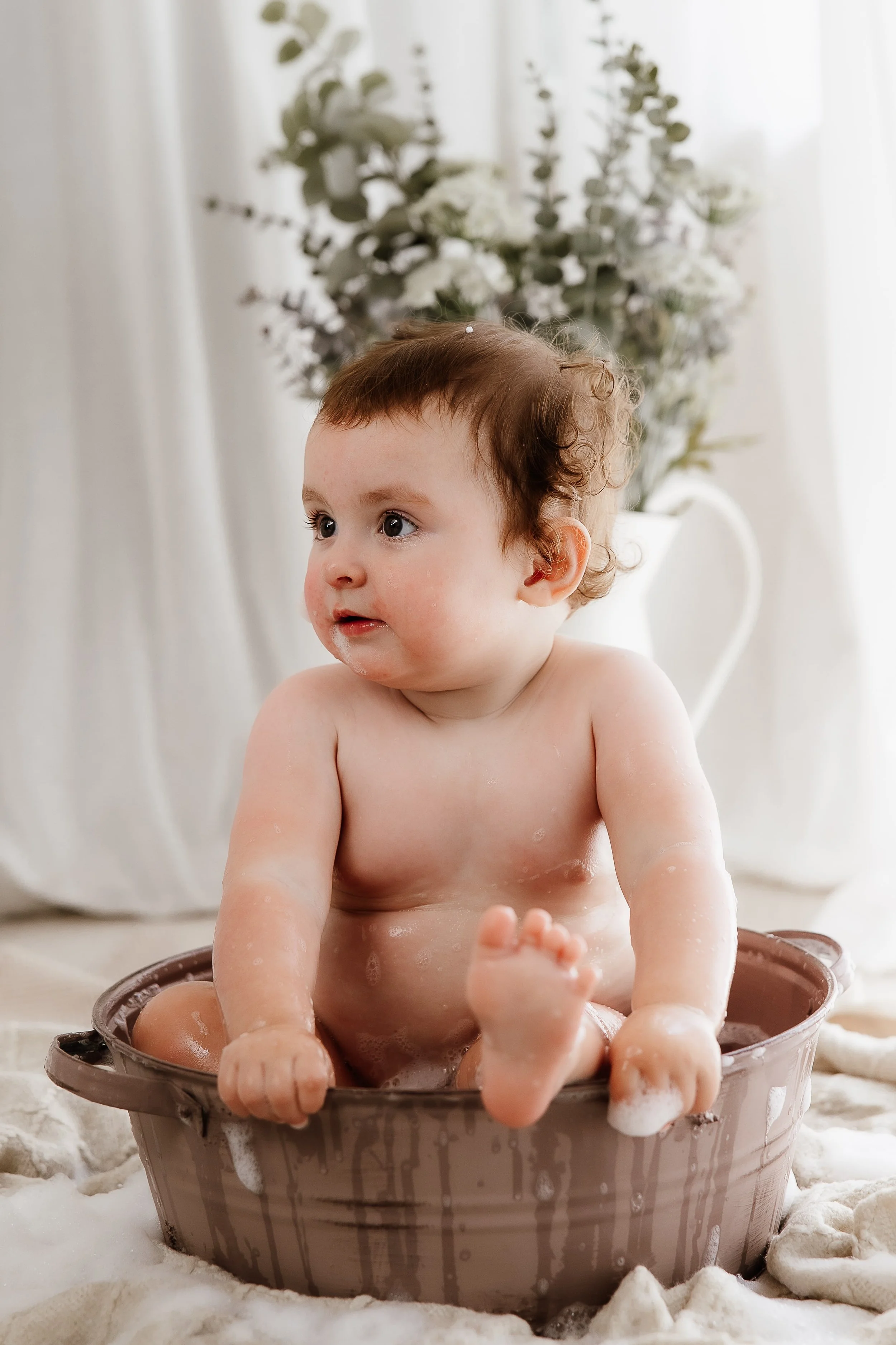 Baby enjoying a bubble bath at the end of a first birthday session in a natural light studio in Derbyshire
