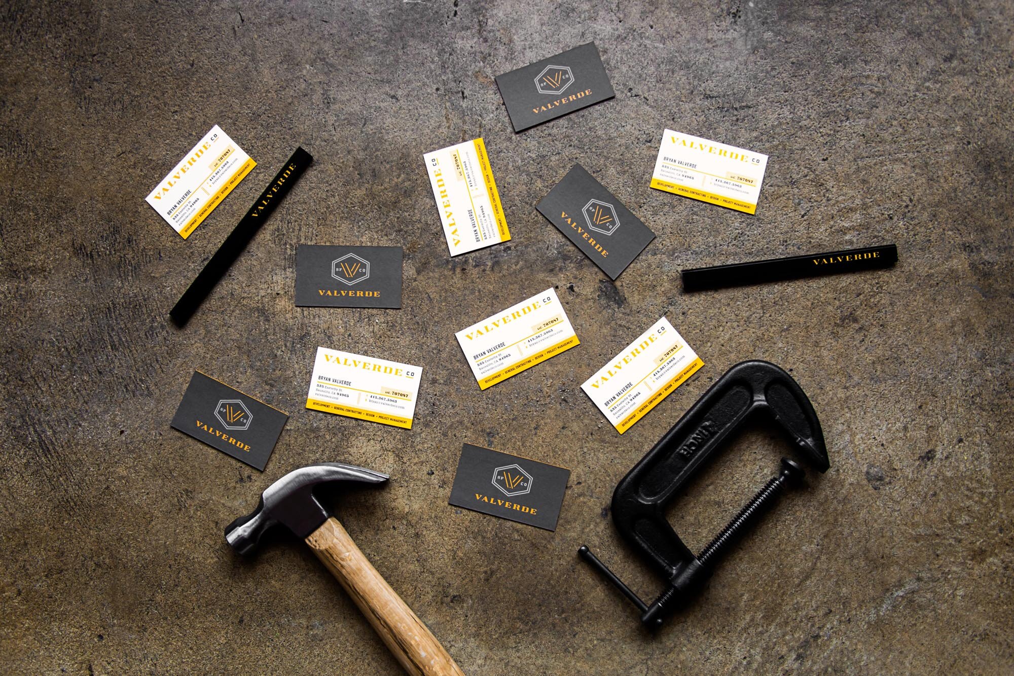 Multiple Valverde Construction business cards surrounded by construction tools on a flat surface