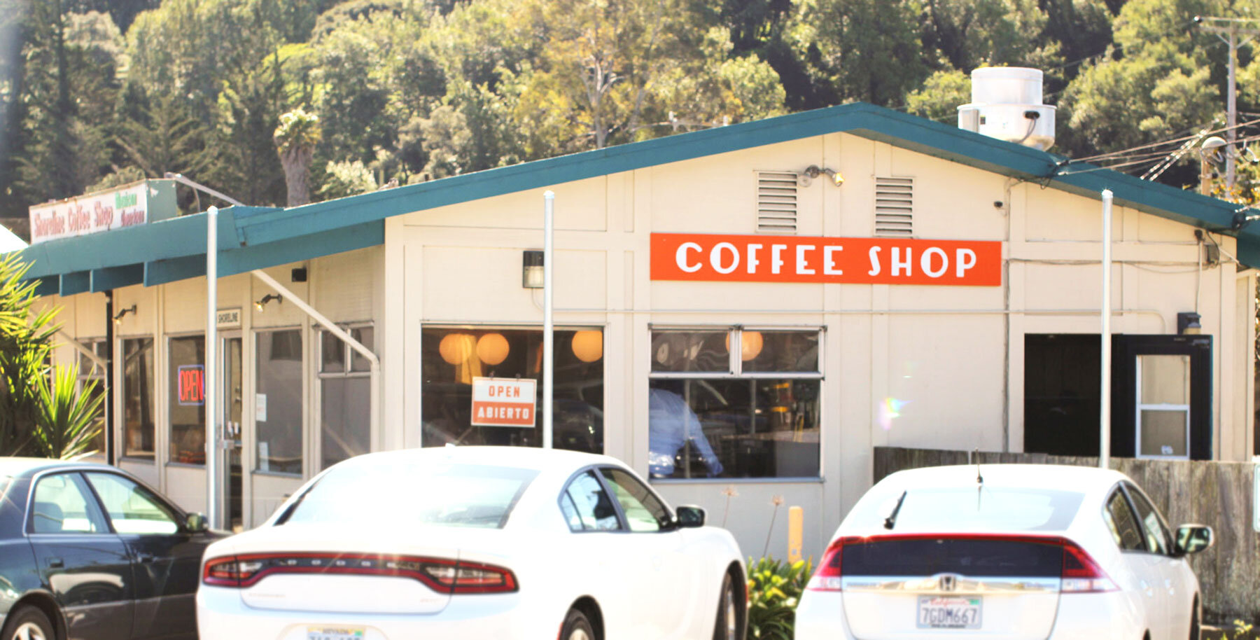 An exterior photo of the Shoreline Coffee Shop with cars parked in front on a sunny day