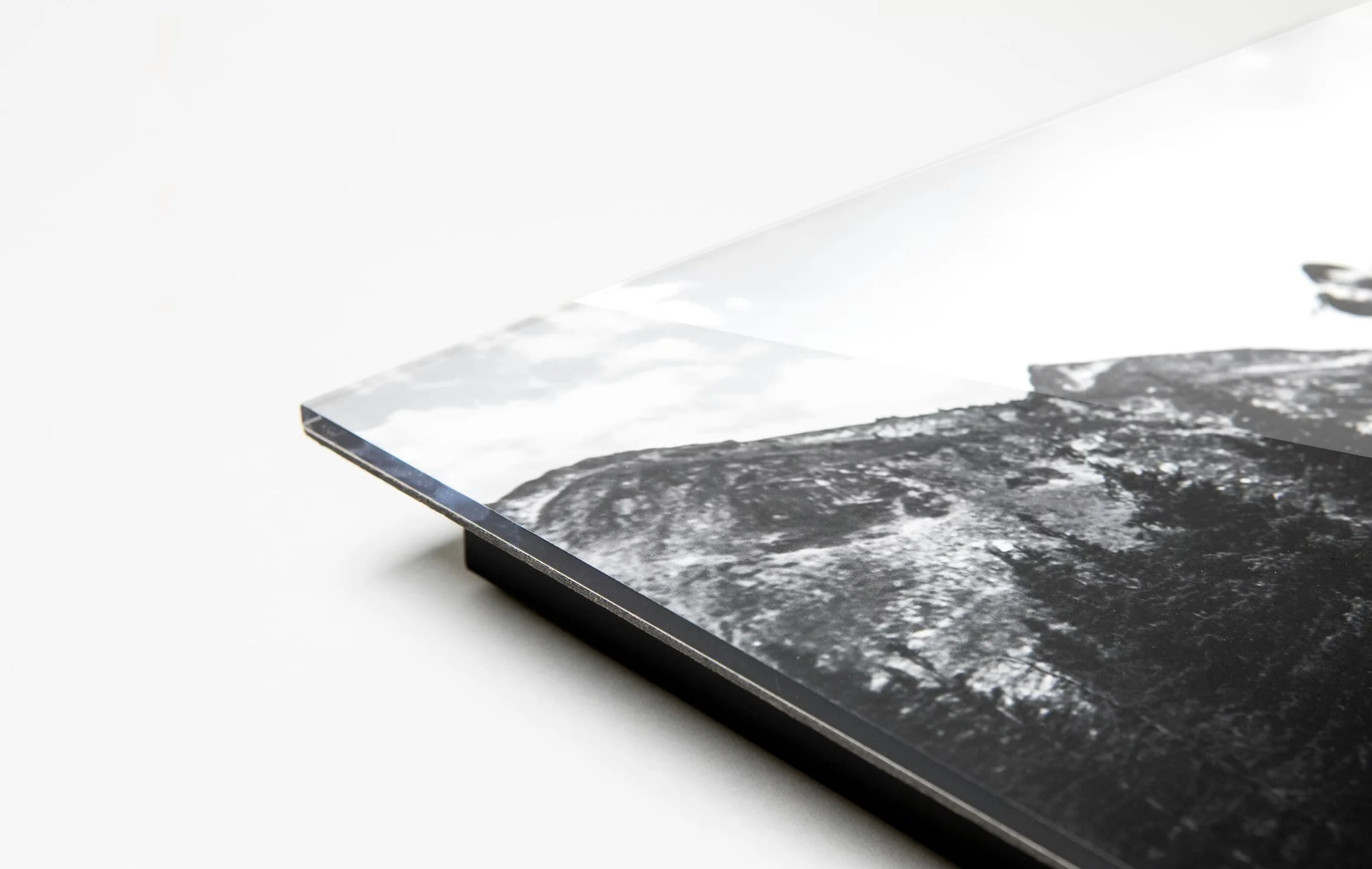 Close-up of a corner of a TV screen displaying a black-and-white landscape photograph, with a white background.