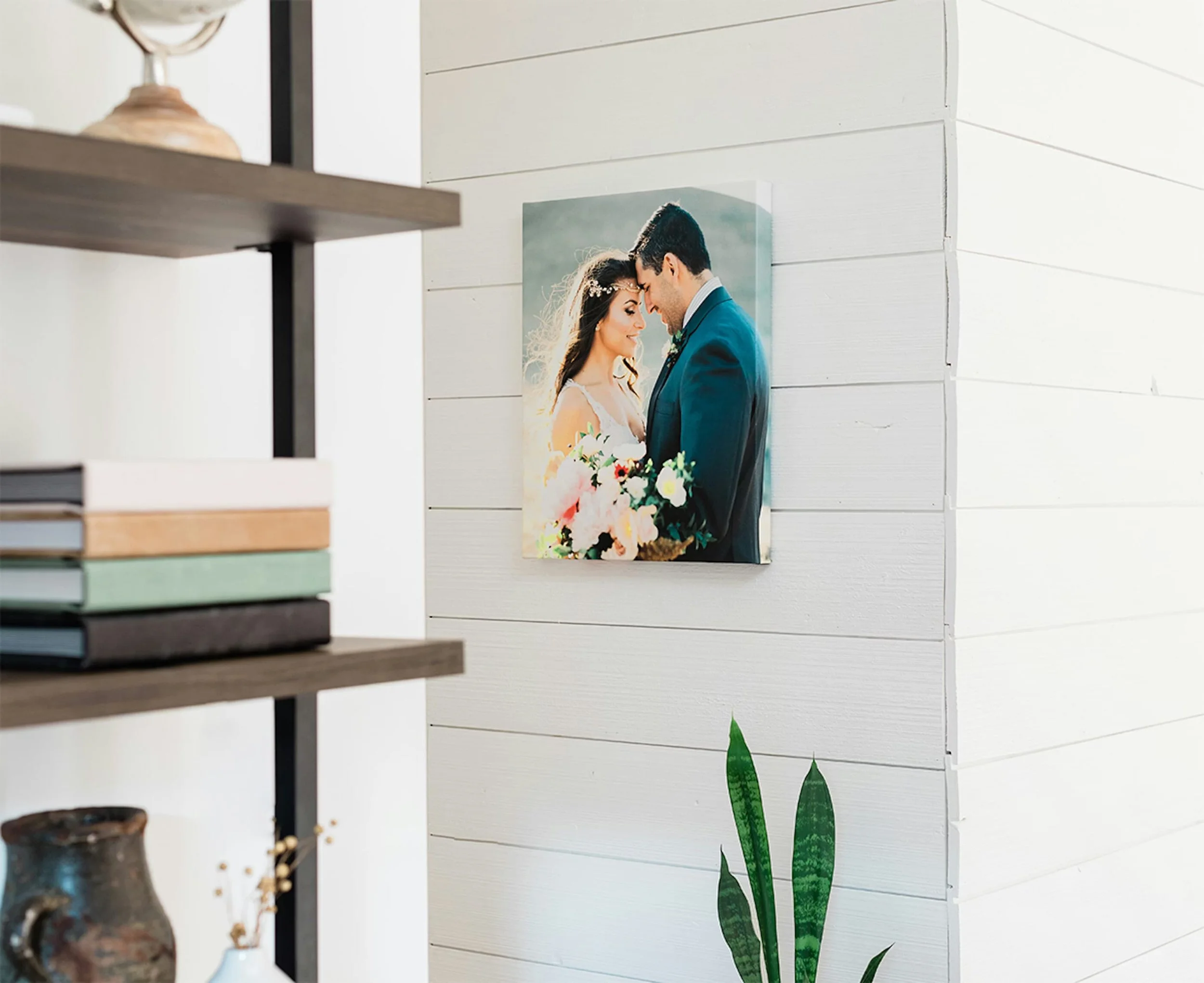 A framed photograph of a bride and groom with foreheads touching, holding a bouquet, hanging on a white shiplap wall in a modern interior space.