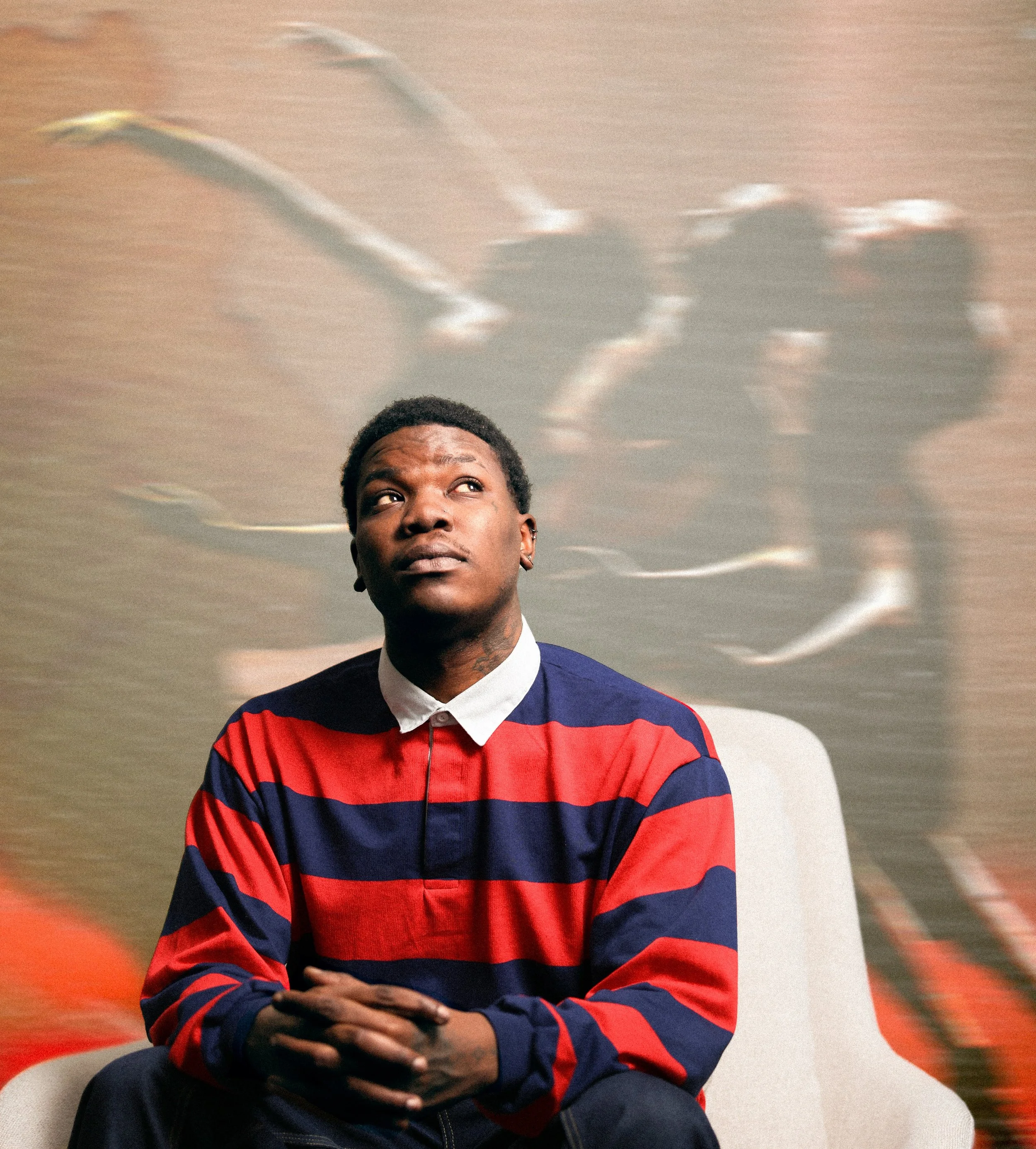 Timothy Hale seated on a white chair in a black and red striped sweater