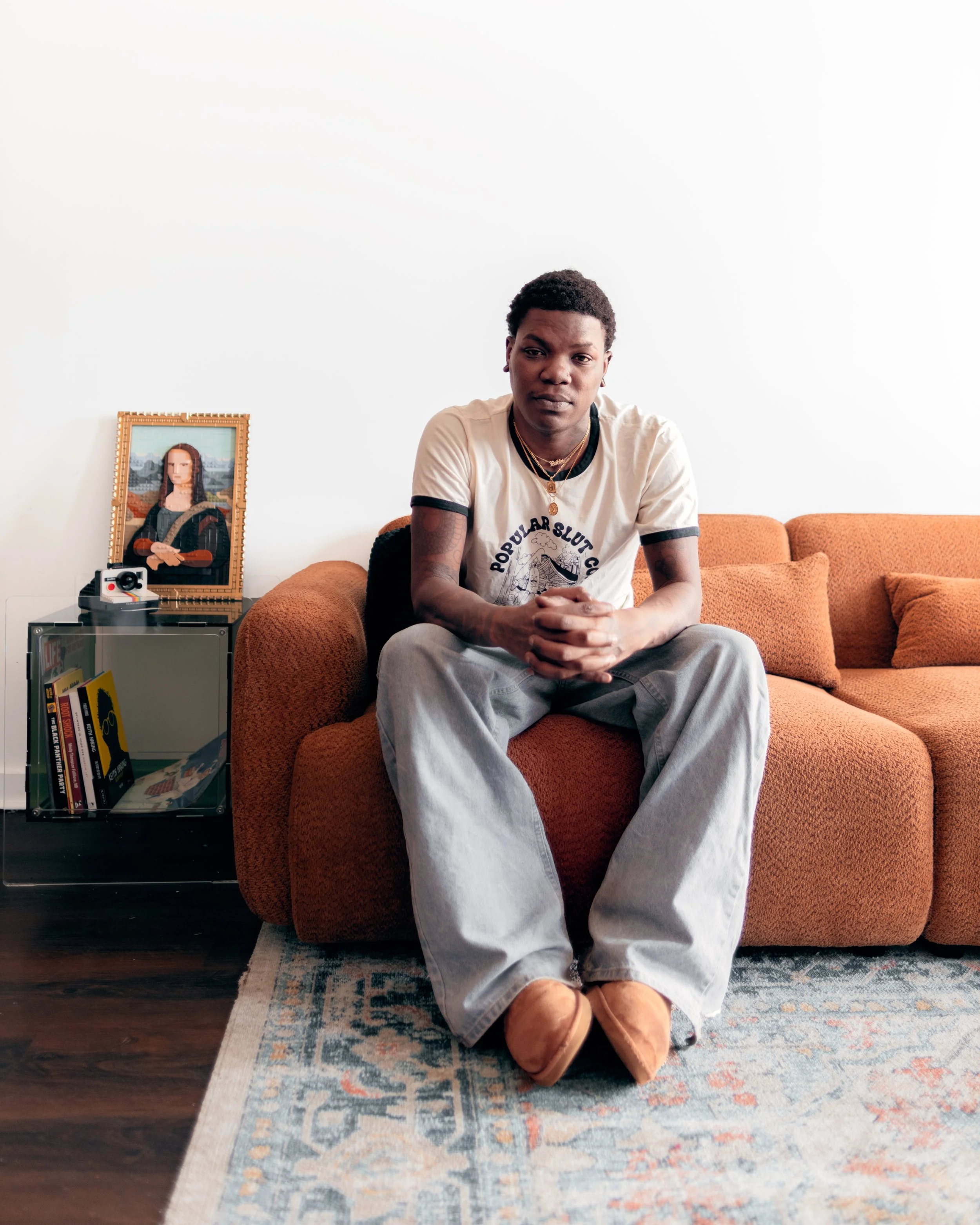Timothy Hale sitting on a rust-colored sofa with his hands clasped