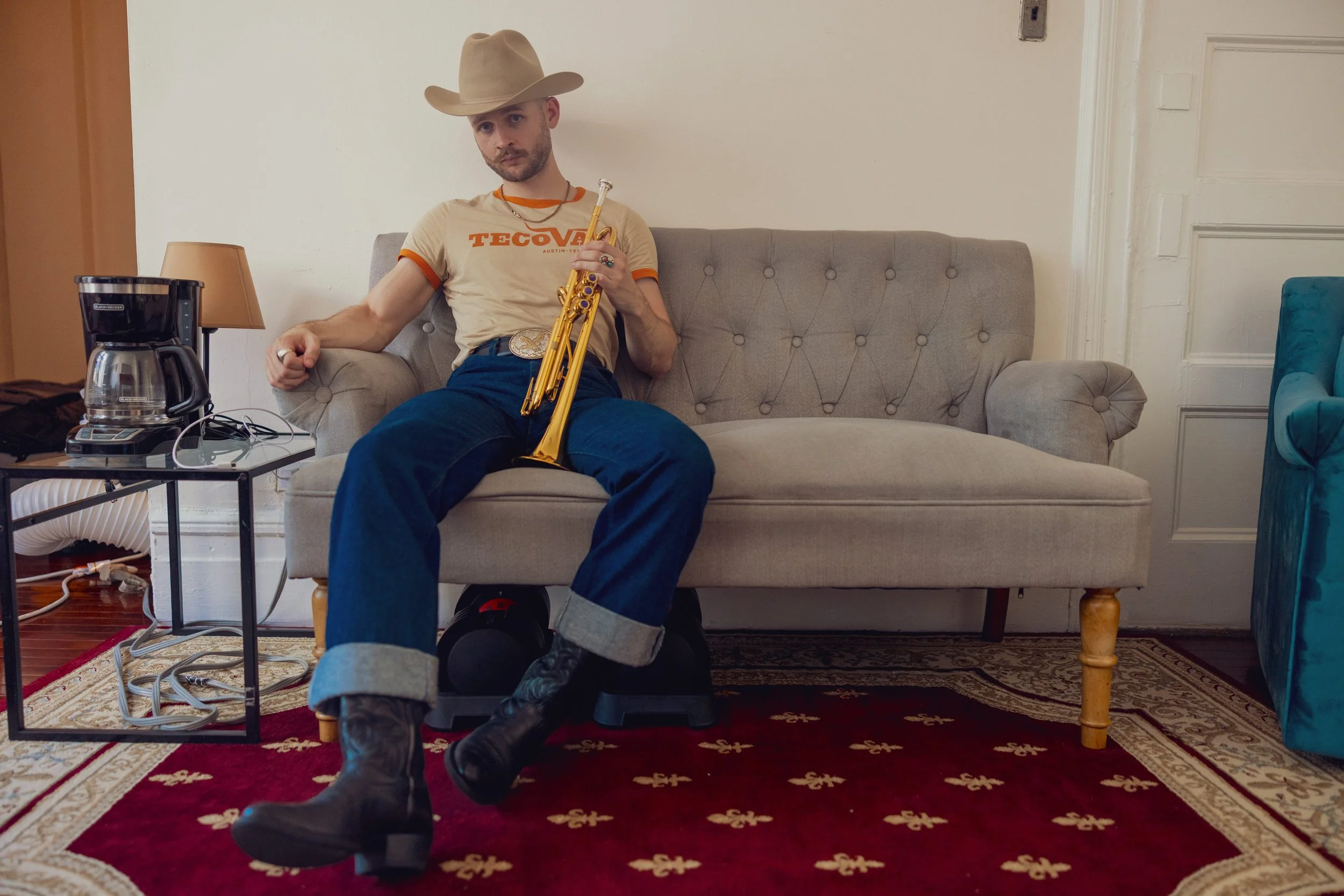 Austin Simmons sitting on a couch at home holding a gold trumpet