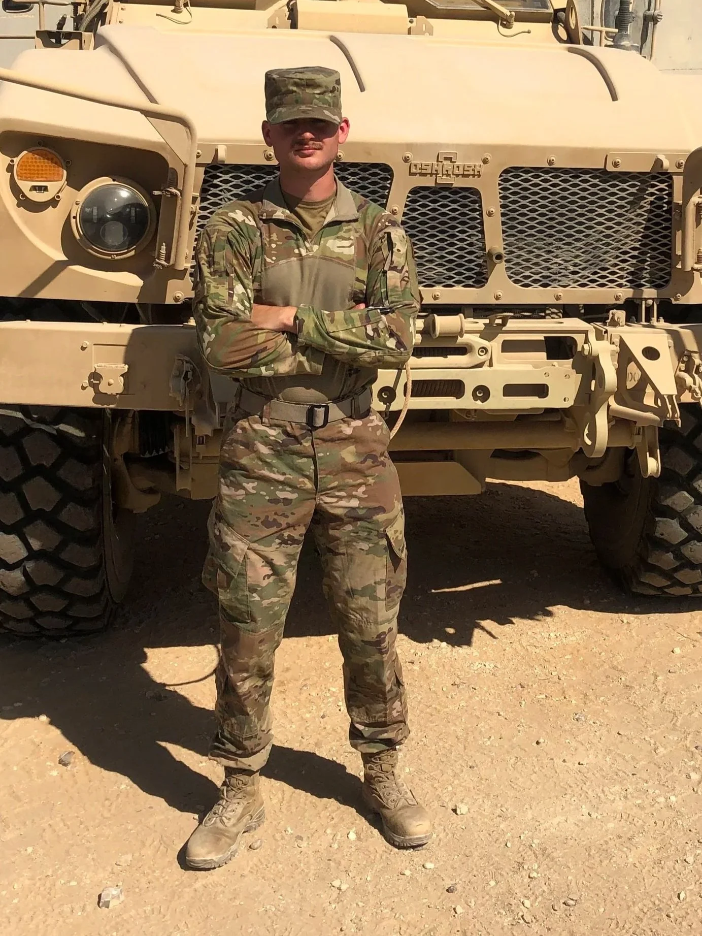 Austin Simmons in uniform standing in front of a military vehicle during his Air Force service