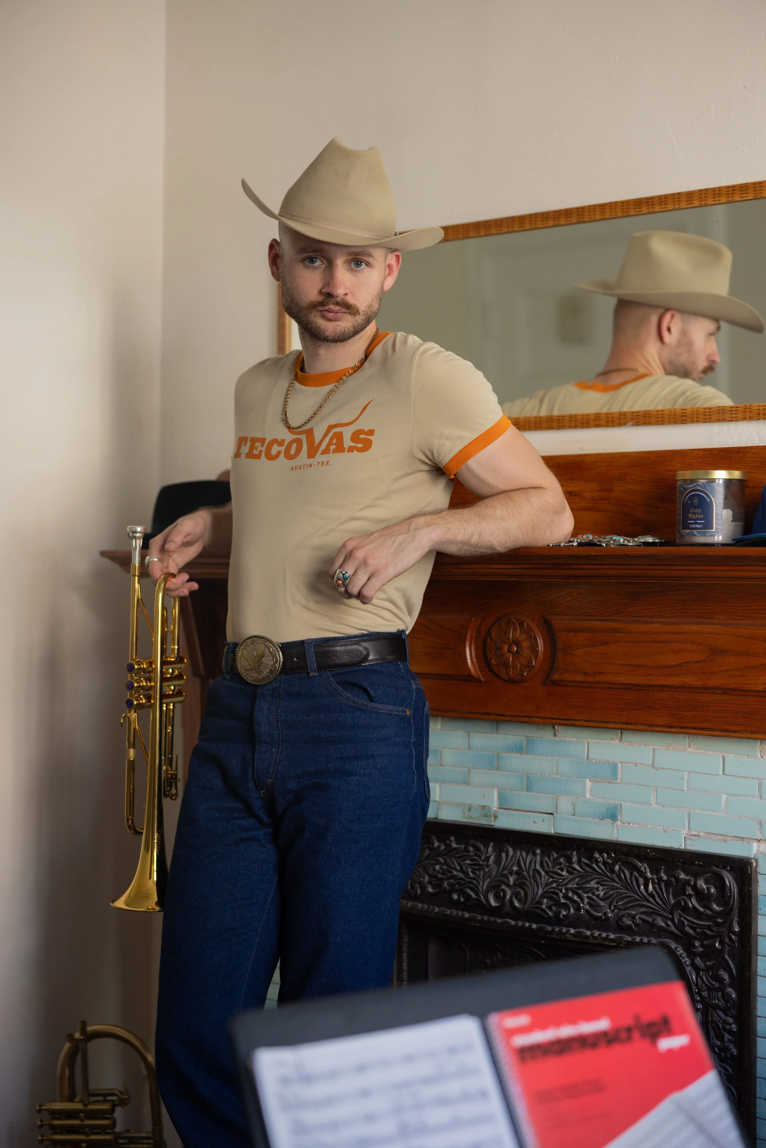 Austin Simmons leaning on a fireplace mantel holding a trumpet