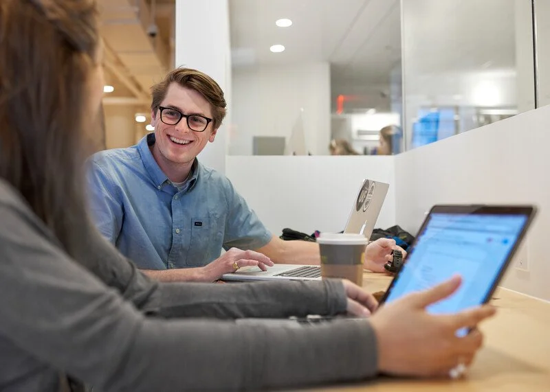 Smiling student in a blue shirt working with a laptop during an advising session at The New School