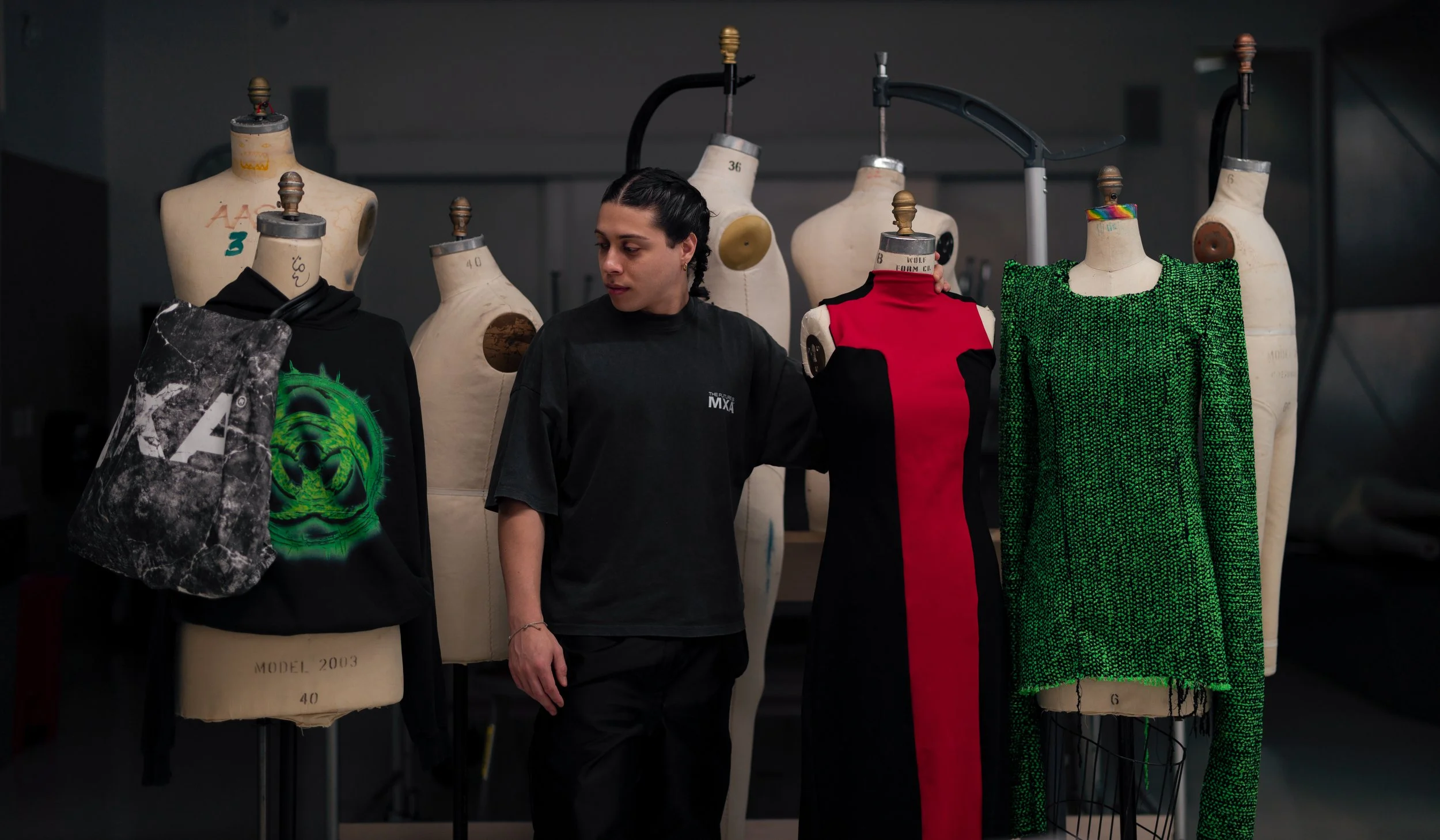 Air Force veteran Giani Rochas Barnes with fashion designs on dress forms at Parsons