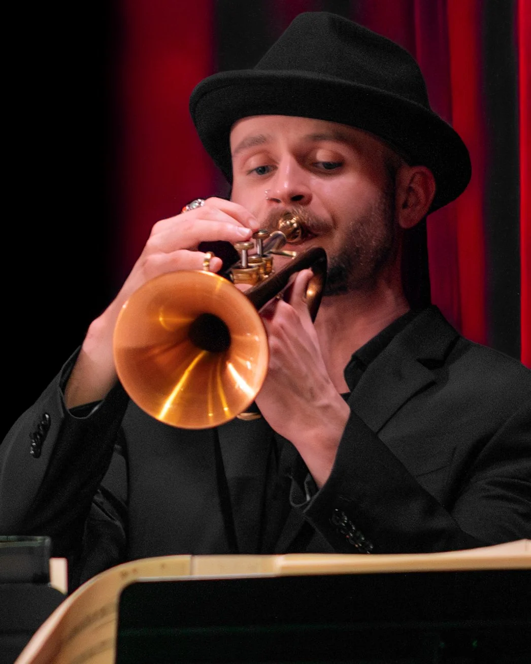 Austin Simmons performing on trumpet in a black hat and suit