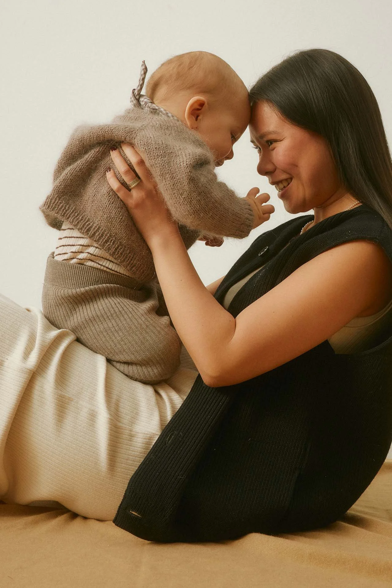 Mother holding her baby and smiling during a close, supportive moment.