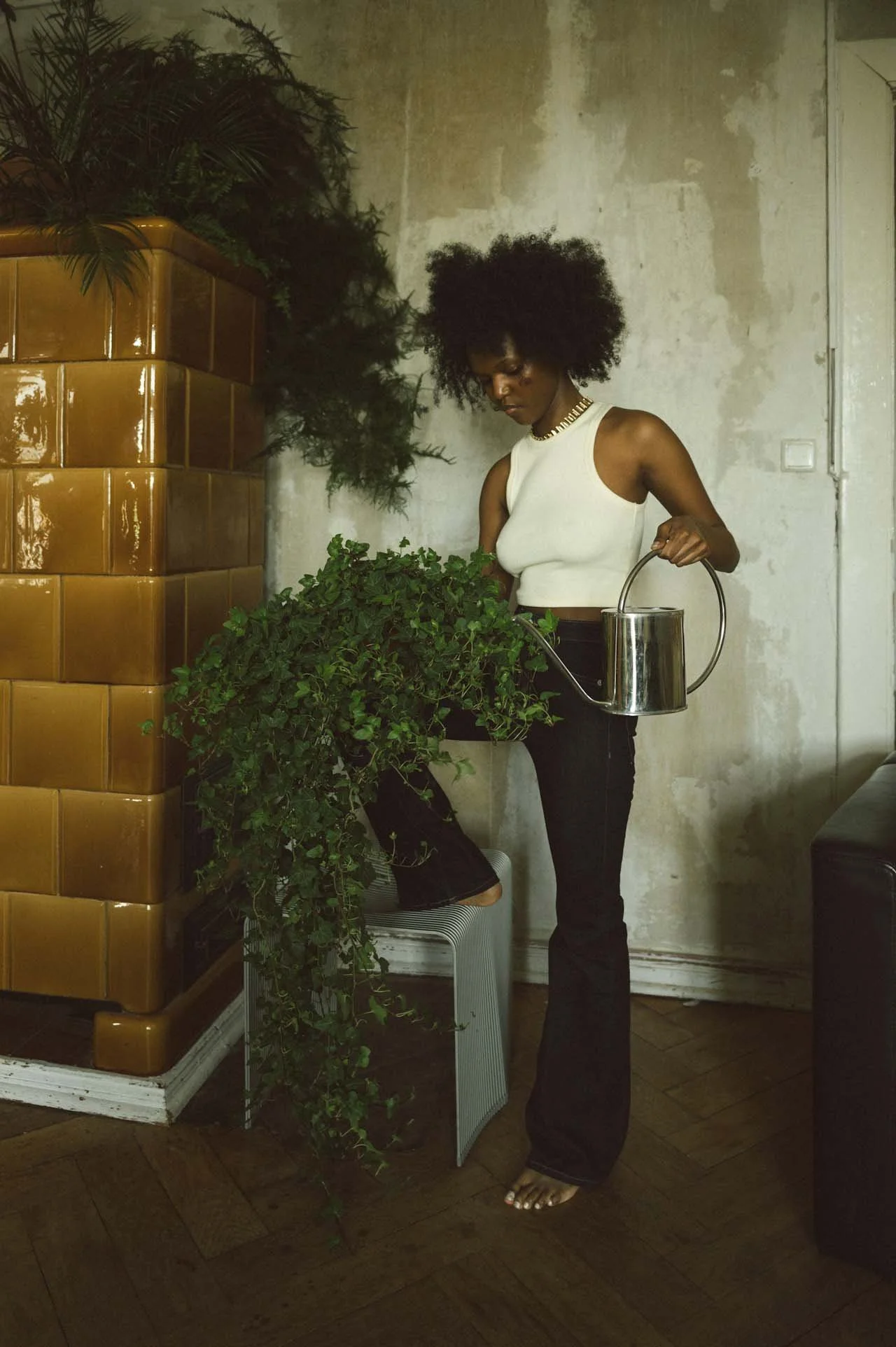 Woman watering plants indoors, representing whole-person wellness and integrative support for reproductive health.