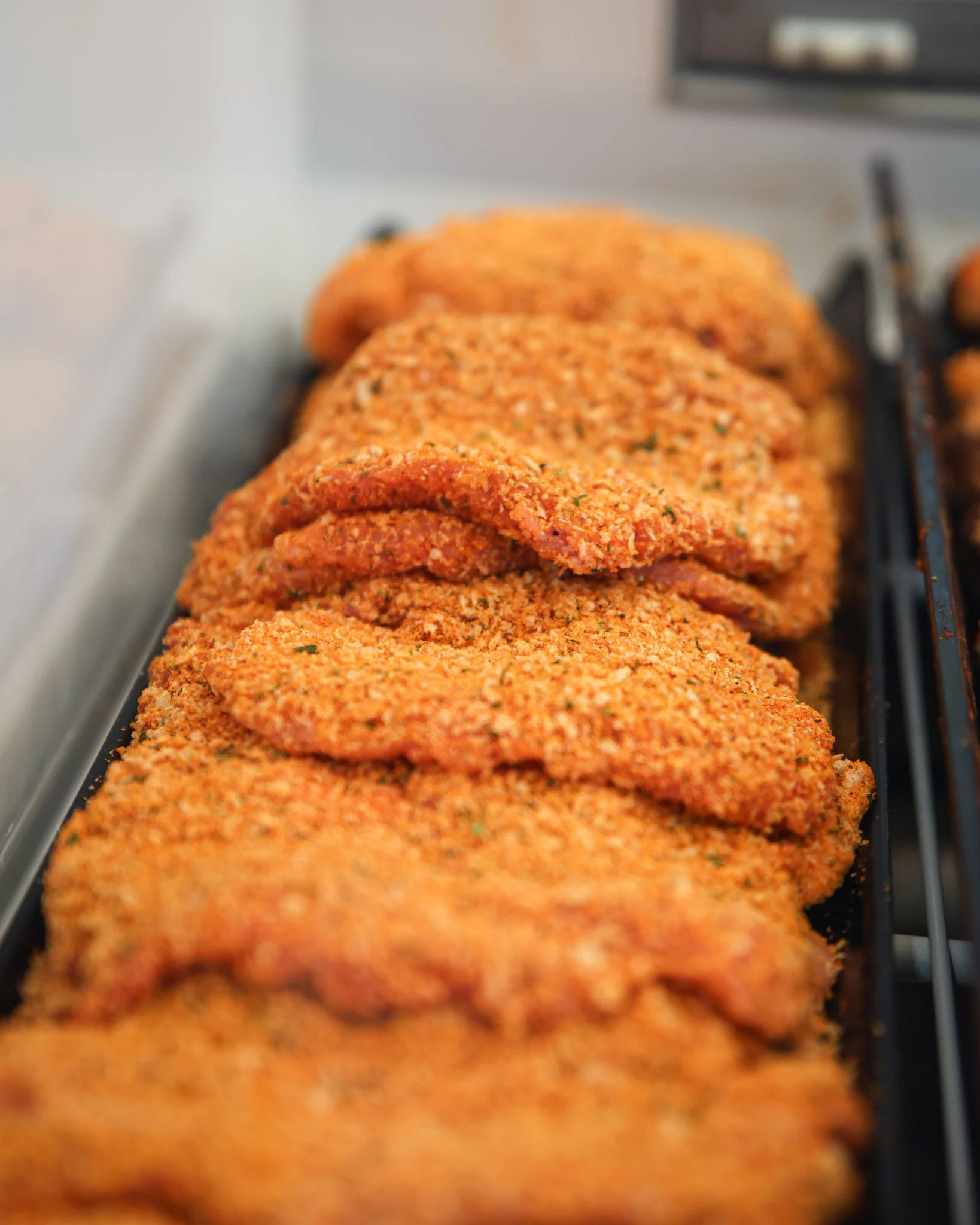 breaded pork cube steak raw and ready to cook, lined up in a row