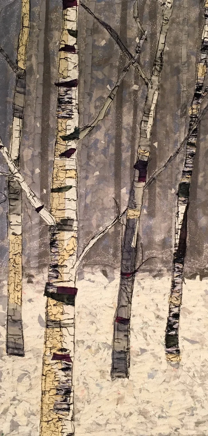 An art quilt of several tall, slender birch trees with white bark and black markings, set against a muted, confetti background, and a snow-covered ground.