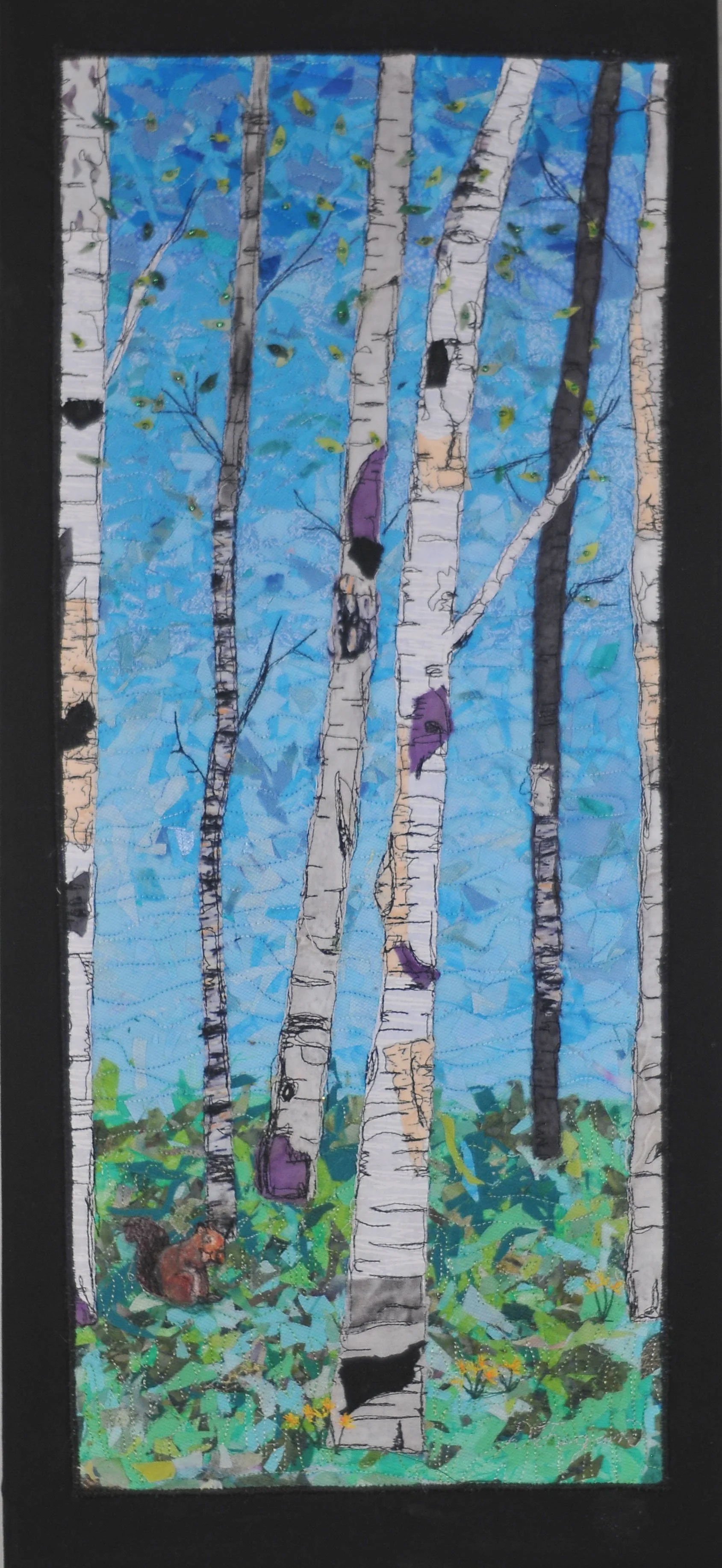 A colorful art quilt of a of a birch forest with bright blue sky, green foliage, and a squirrel at the bottom left corner.