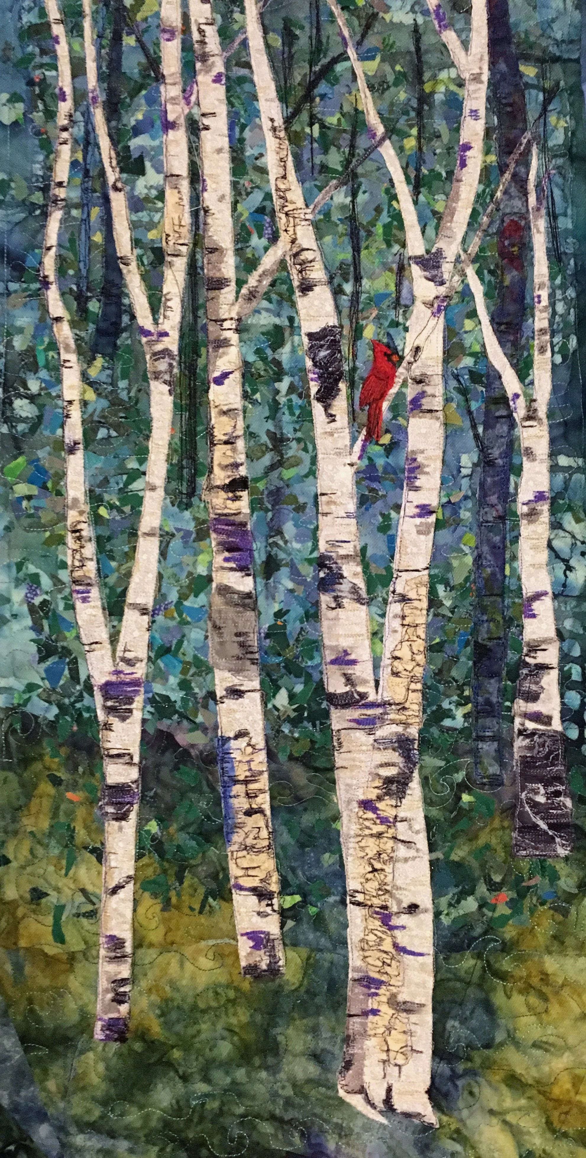 A quilted artwork depicting a forest scene with tall aspen trees and a red cardinal bird perched on a branch.