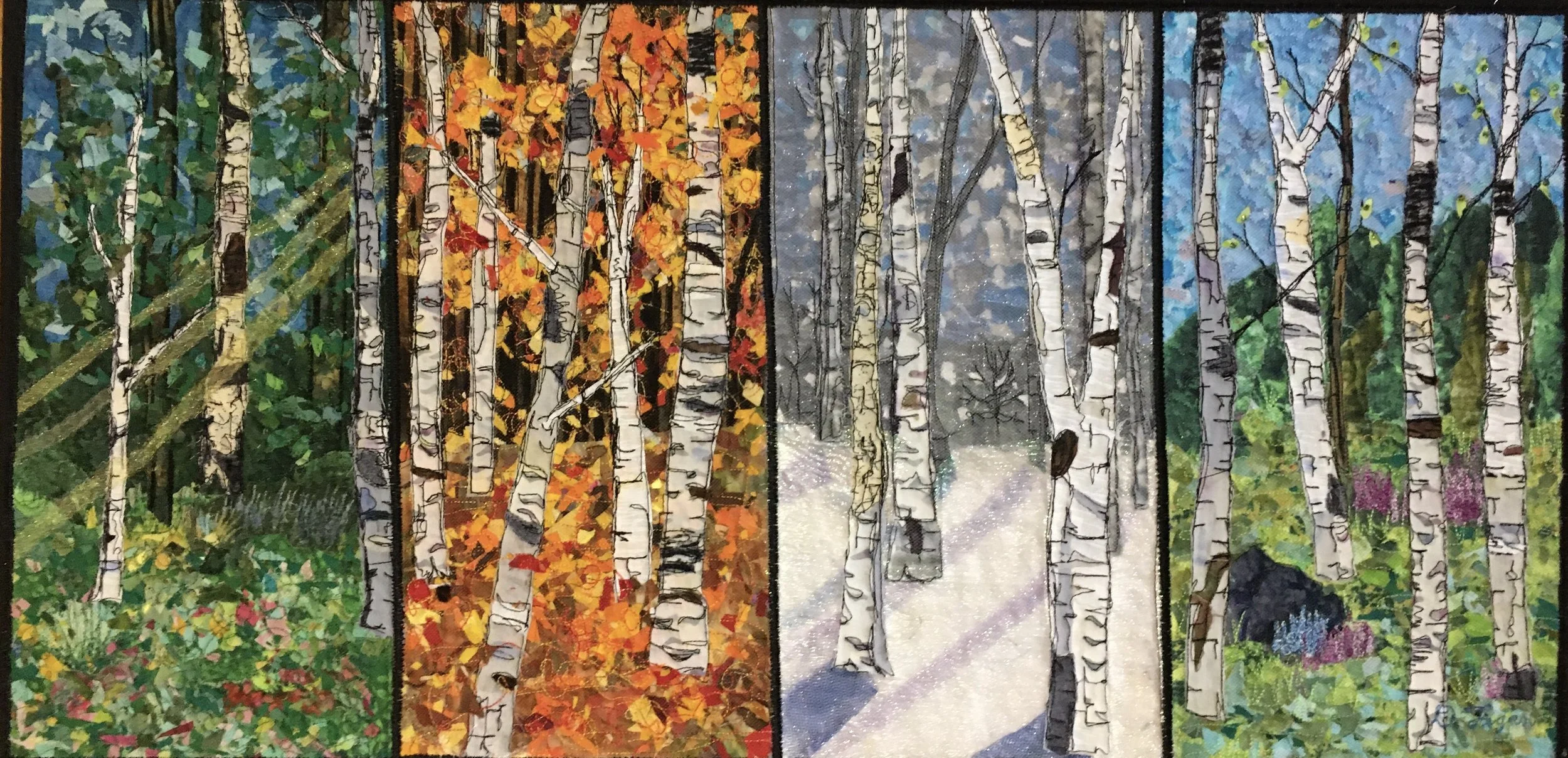 An  art quilt depicting seasonal changes in a forest with four sections: autumn with yellow and orange leaves, winter with snow and bare trees, spring with green leaves and purple flowers, and summer with lush green foliage.