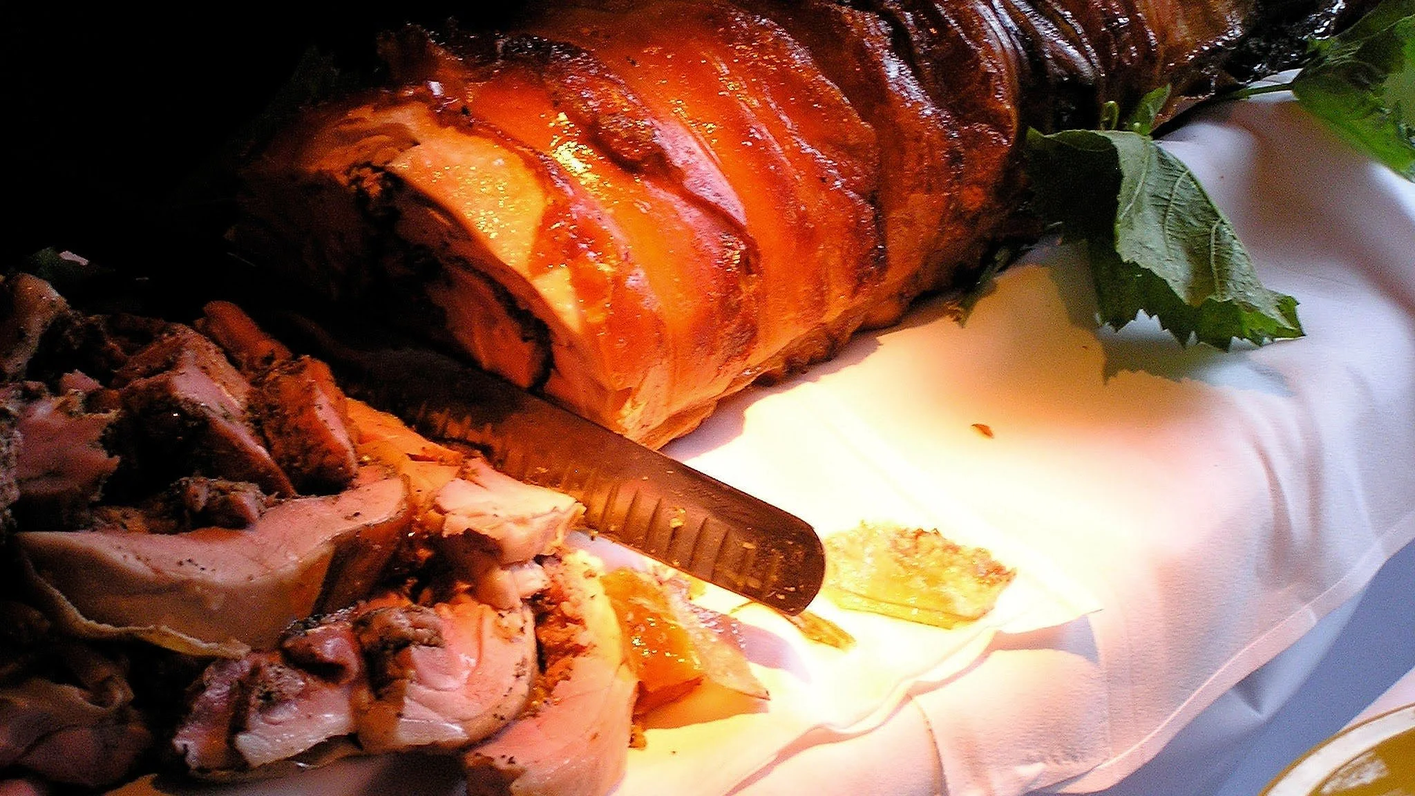 Roast meat on a white cloth with slices cut and a carving knife.