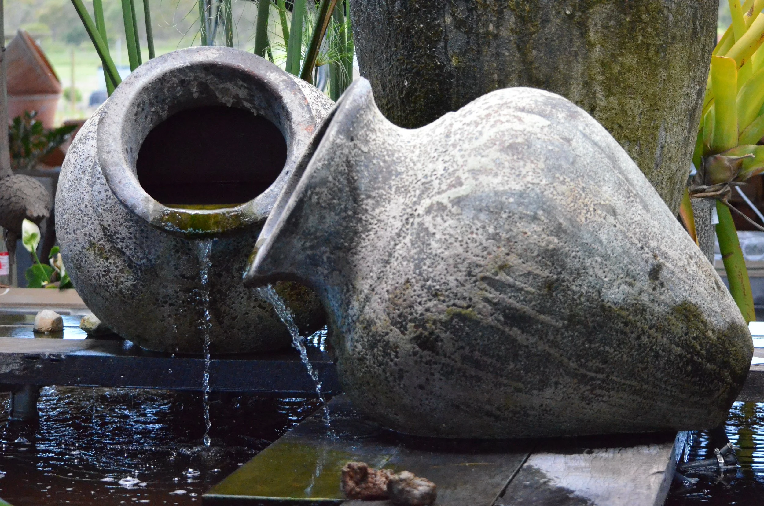 A decorative stone fountain shaped like a fish, with water flowing from its mouth into a water basin.