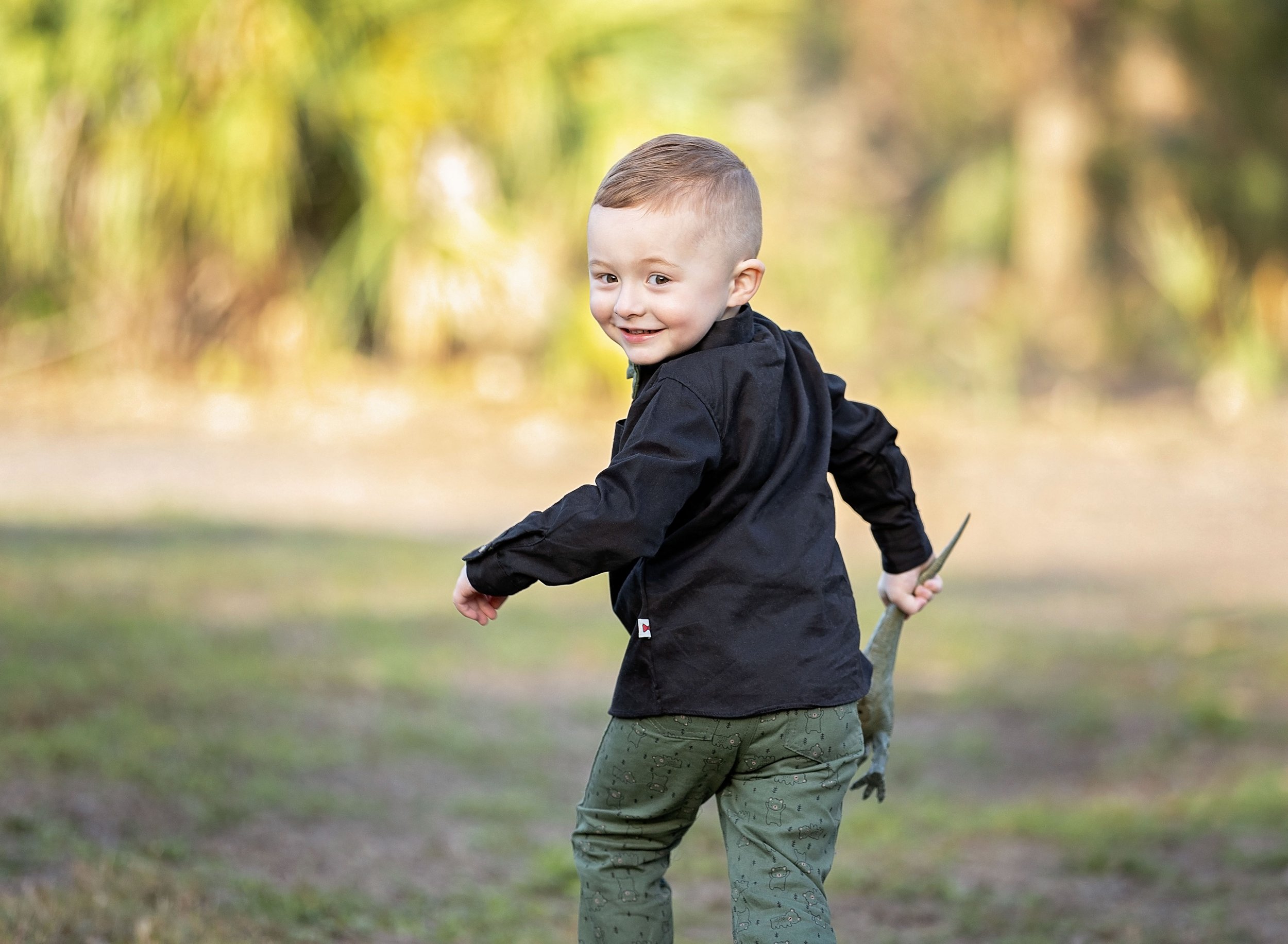 Three year old boy in park holding his dinosaur in North Port FL