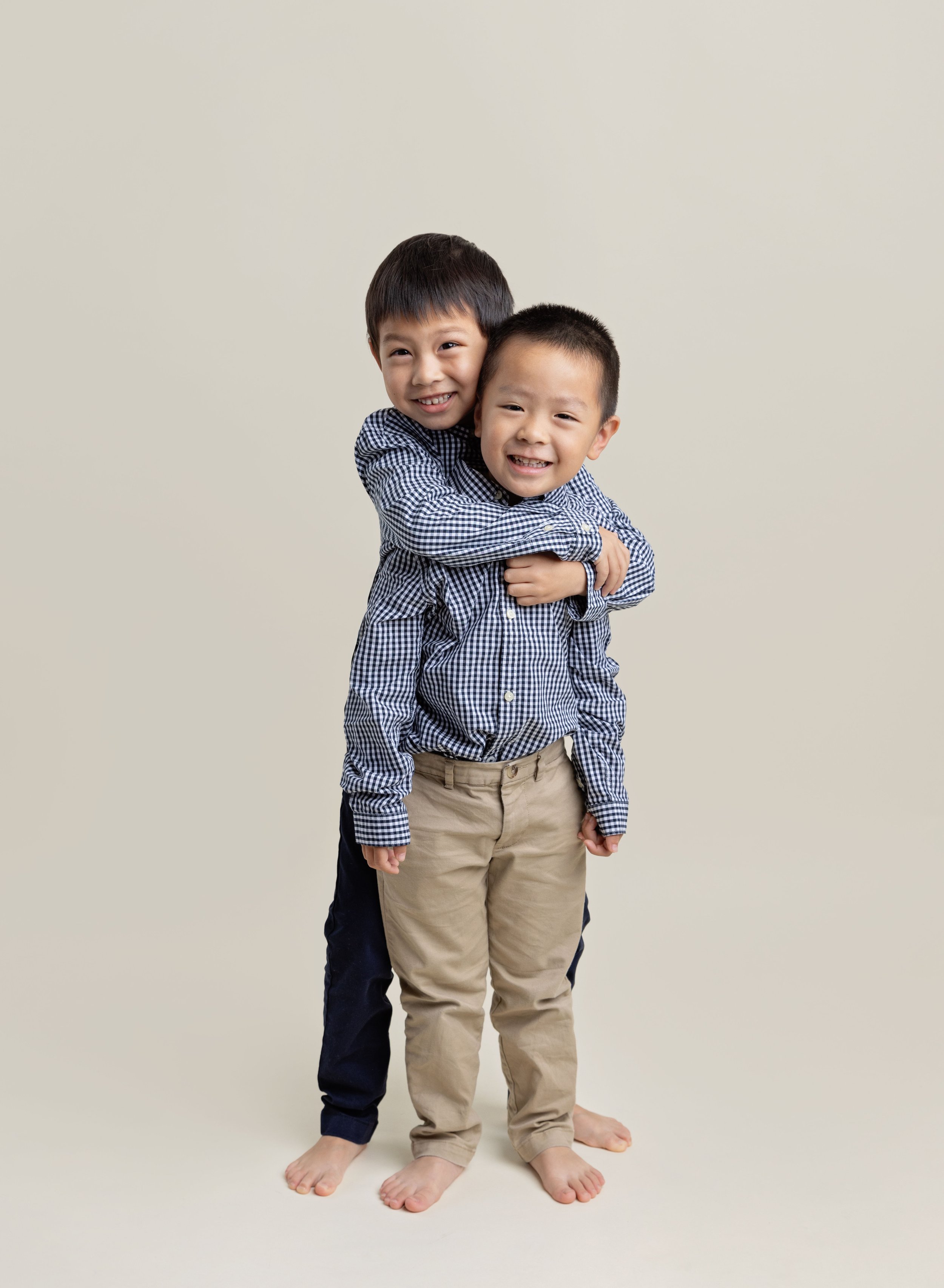 Two young brothers hugging on cream backdrop in Port Charlotte FL photo studio