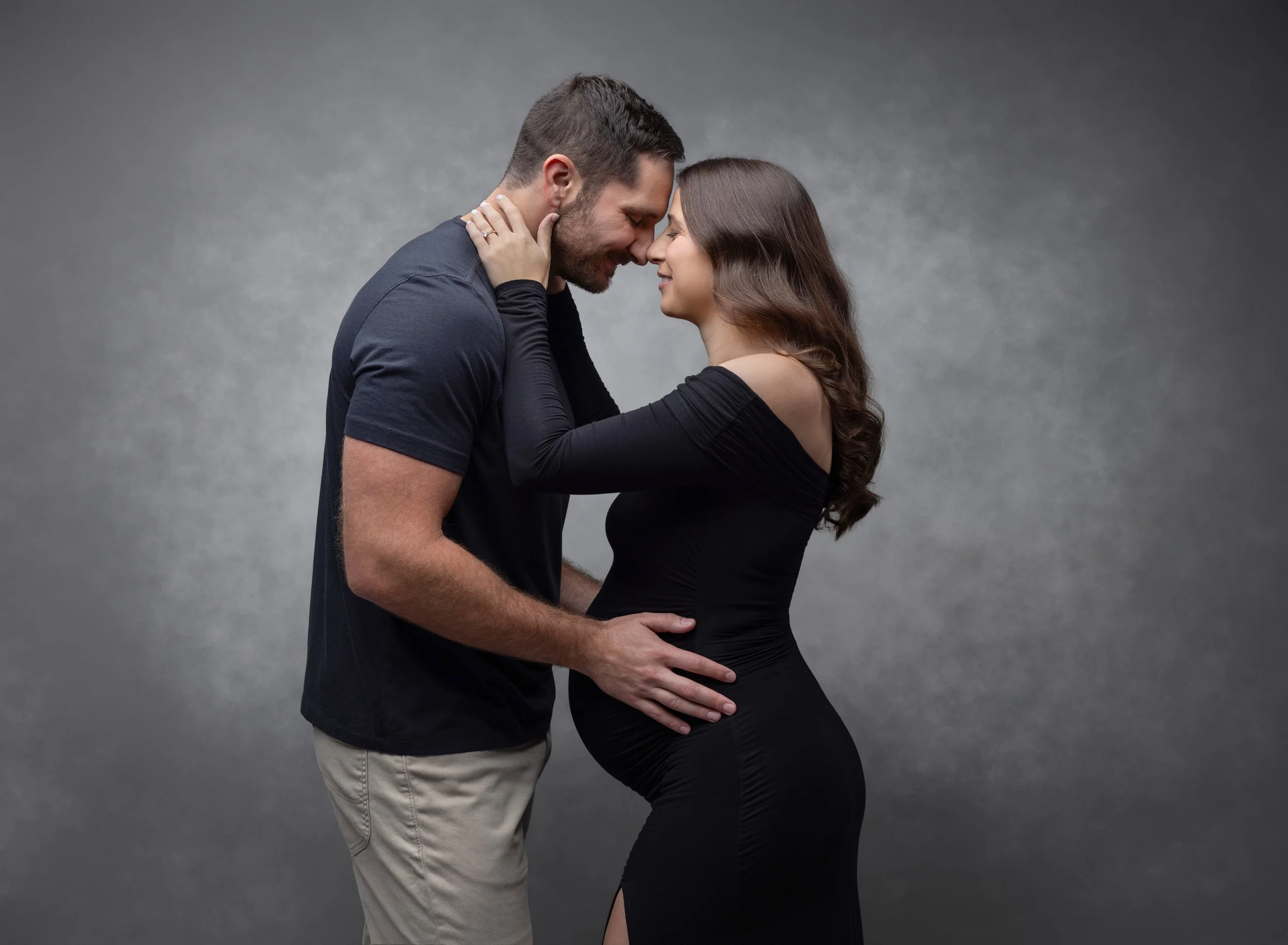 Pregnant mom facing dad in black maternity gown in Fort Myers photo studio