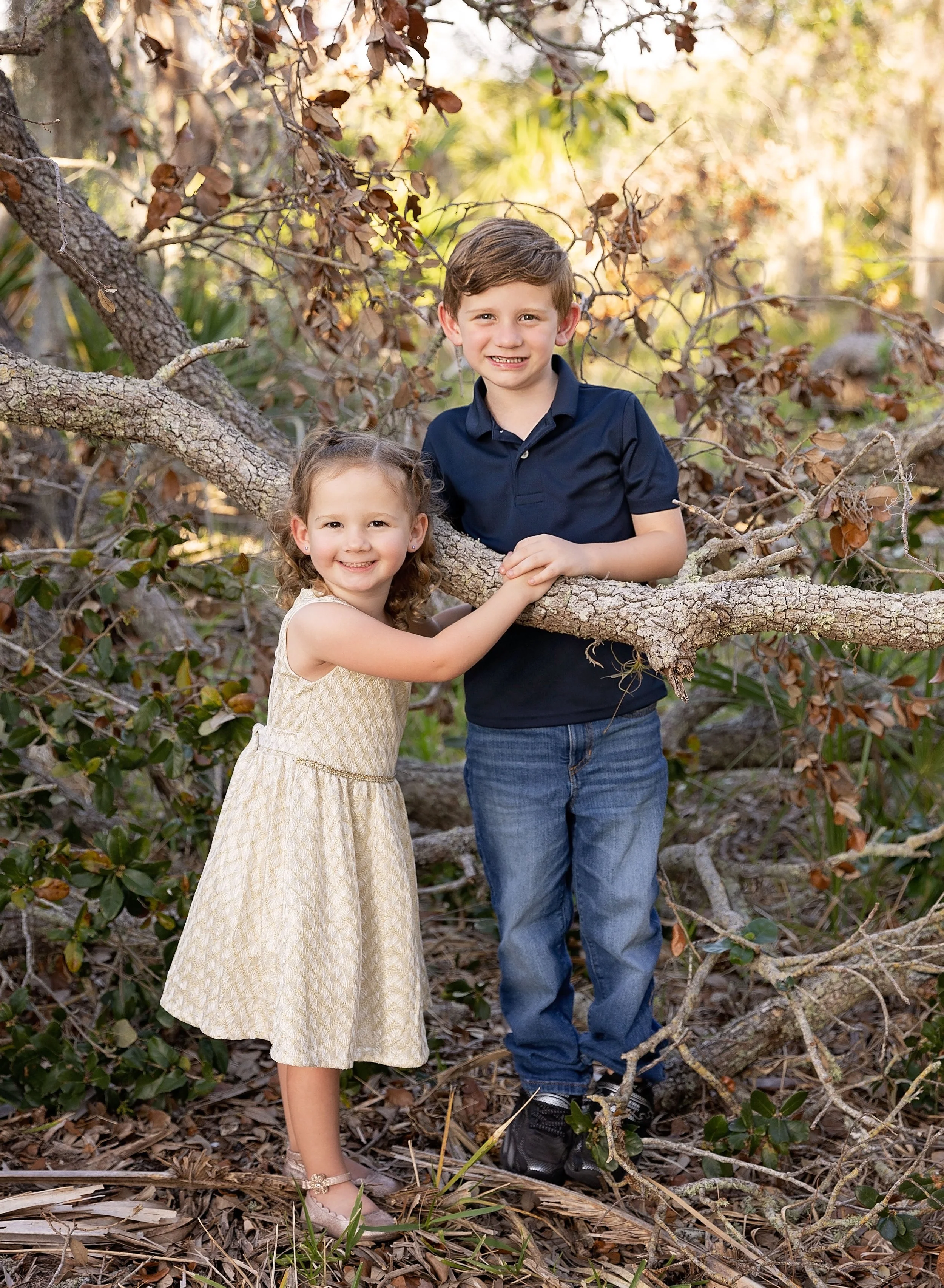 Big brother and little sister posing by a tree in Venice FL park