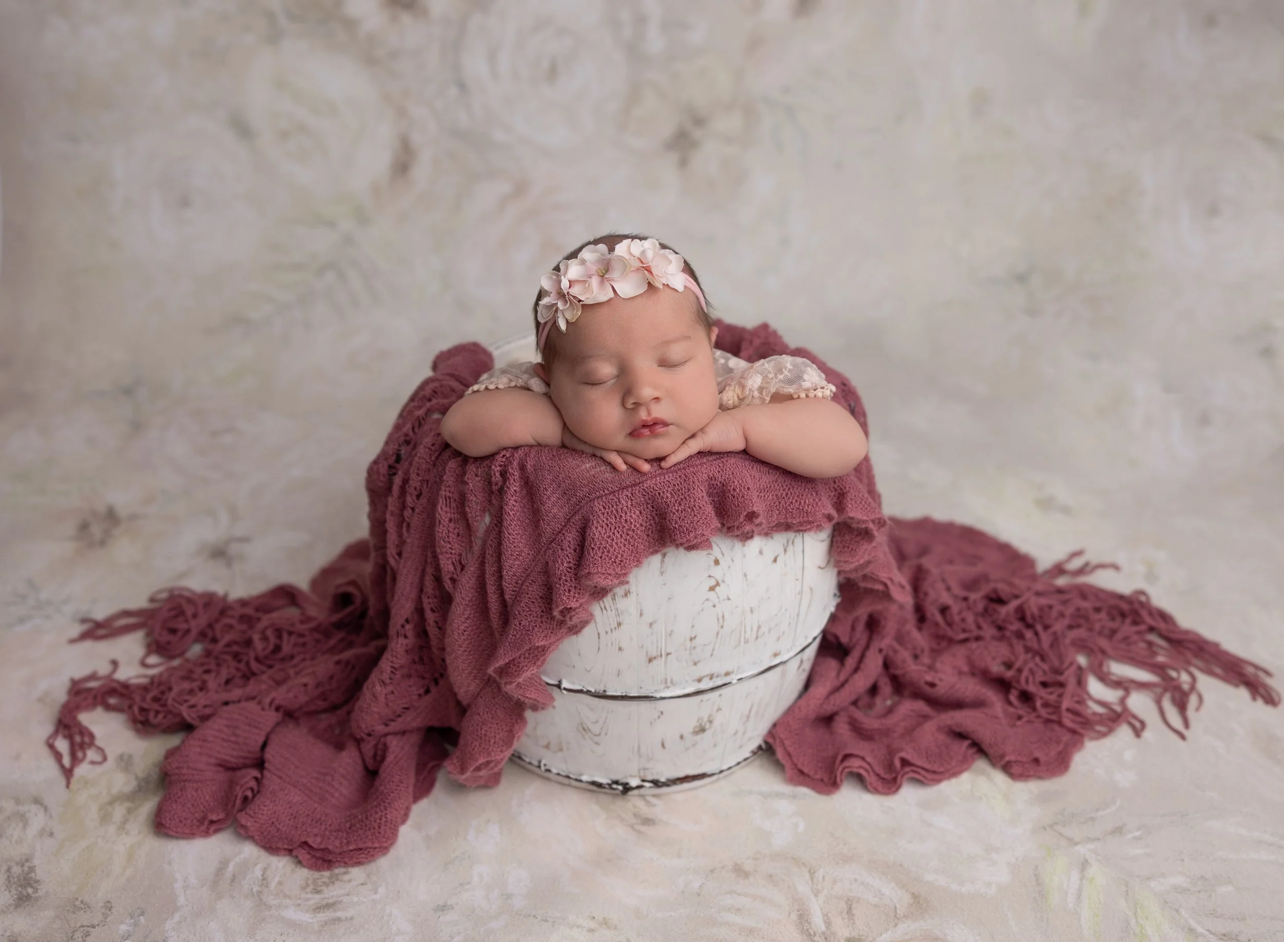 Newborn girl in bucket prop with flowers North Port photo studio