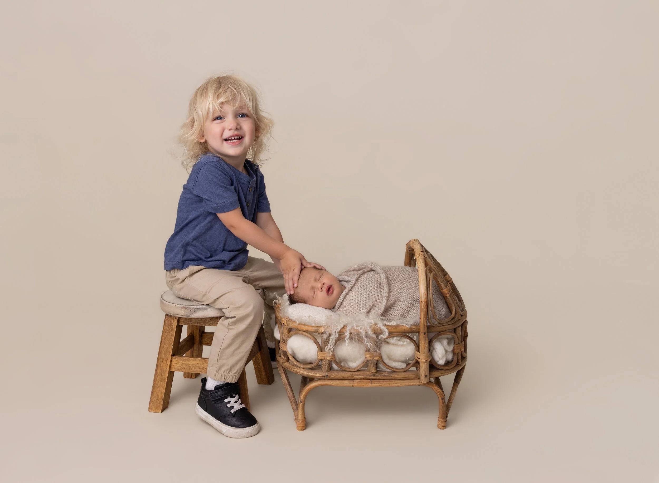 Big brother with newborn brother in cream in Port Charlotte FL photo studio.