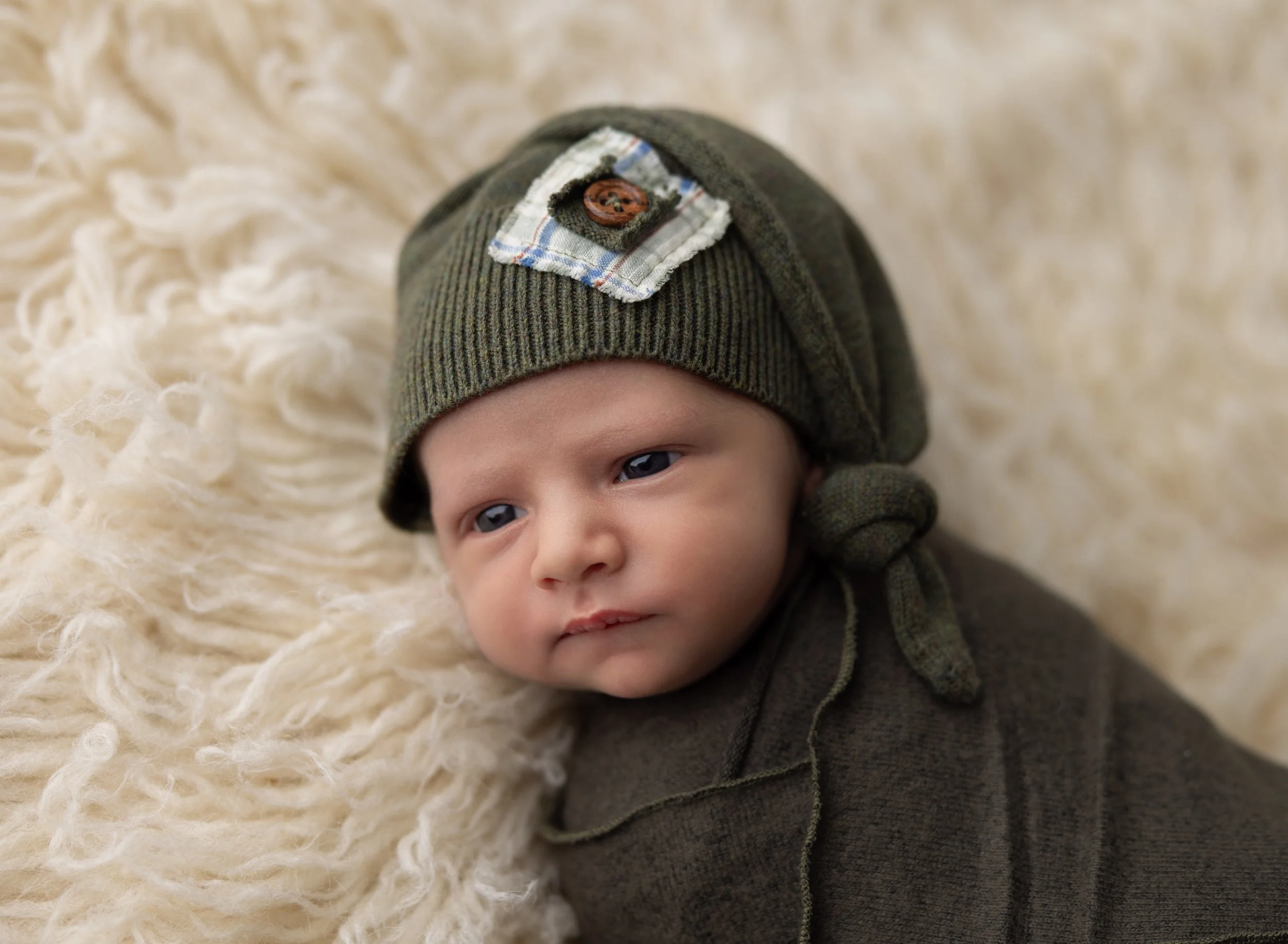 Newborn boy in green swaddle with eyes open in Fort Myers, FL